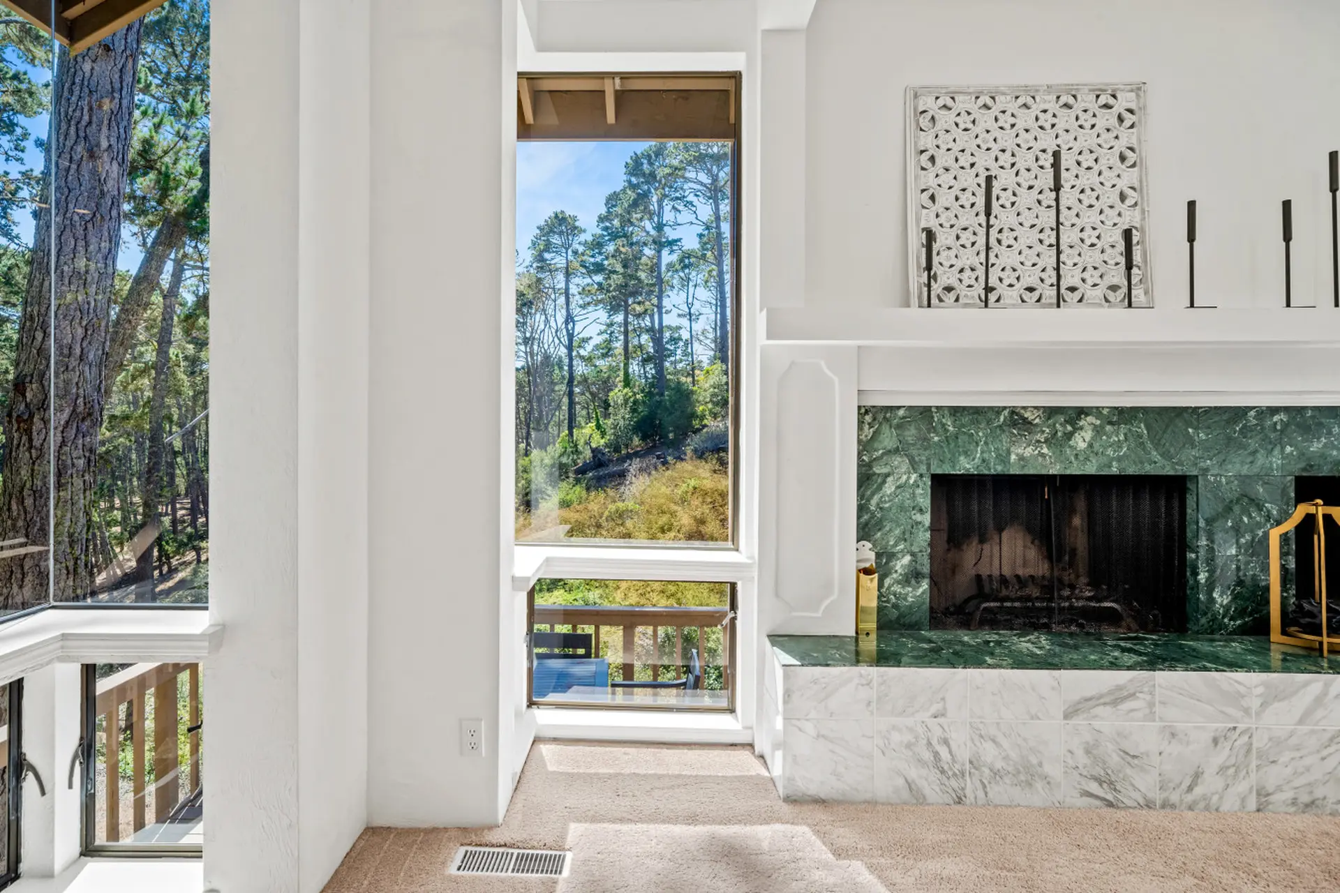 Interior view of a living room with a green marble fireplace and large windows.