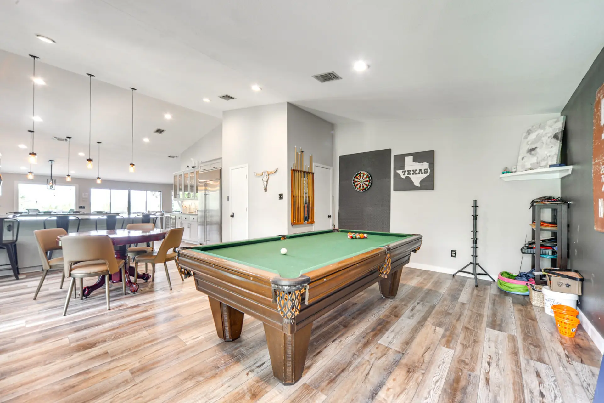A billiards room with a pool table, dartboard, and Texas-themed decor.
