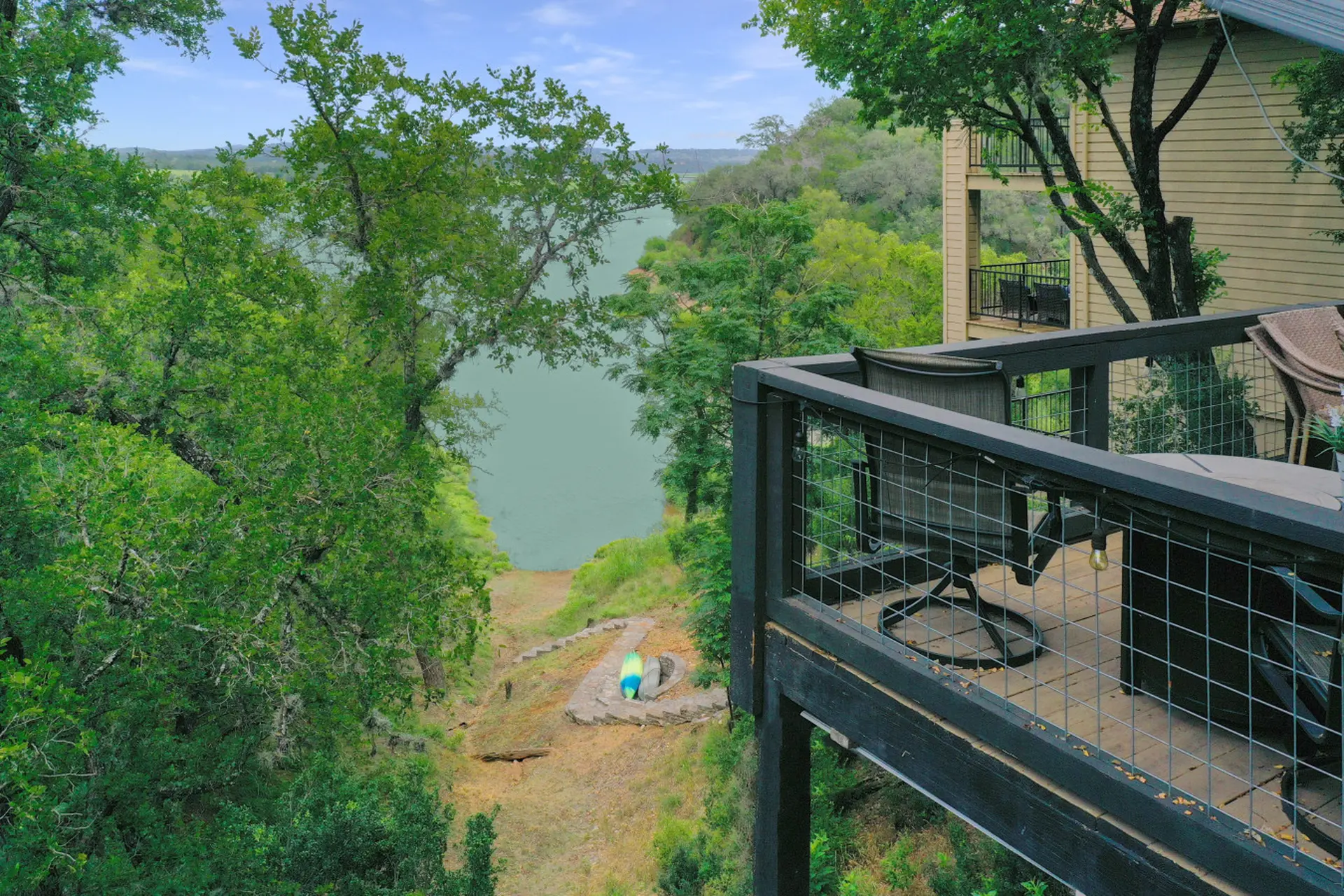 Deck overlooking a lake with trees and a building.