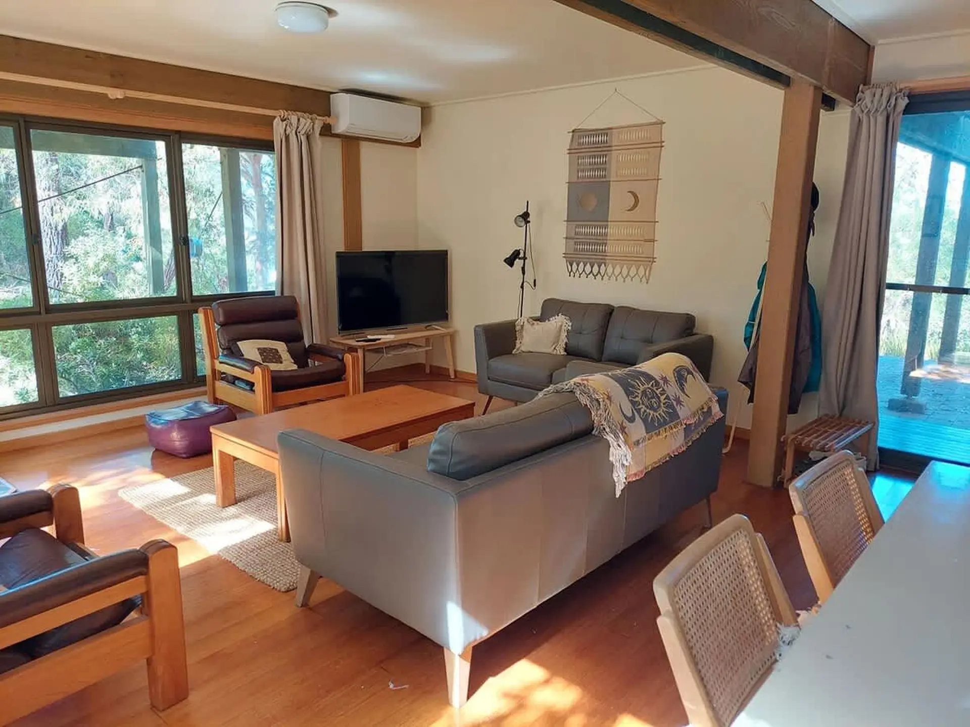 Cozy living room with wooden beams, leather chairs, a sofa, and a TV.