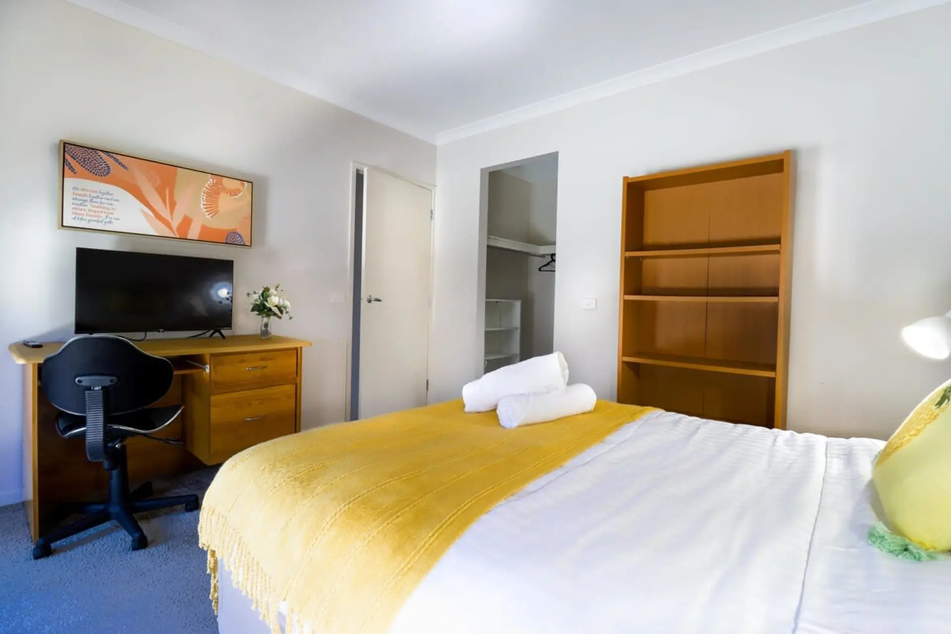 A bedroom with a bed, desk, and bookshelf.