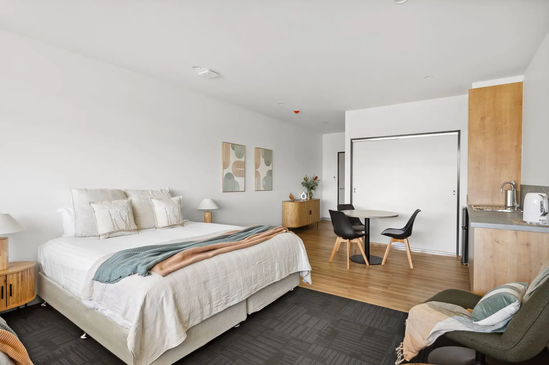 A studio apartment with a bed, dining table, kitchen, and seating area.