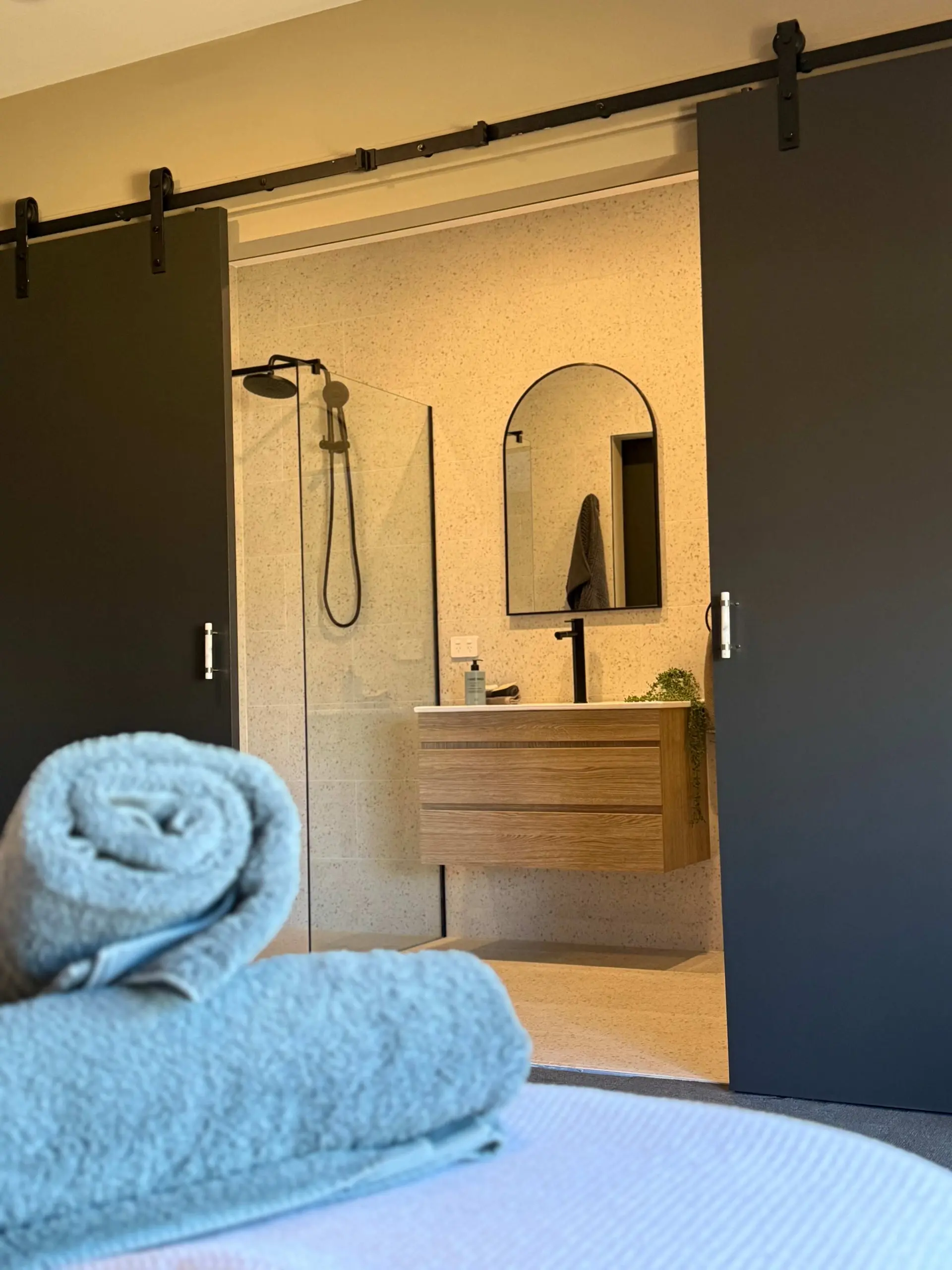 A modern bathroom with a sliding door reveals a shower, vanity, and mirror.