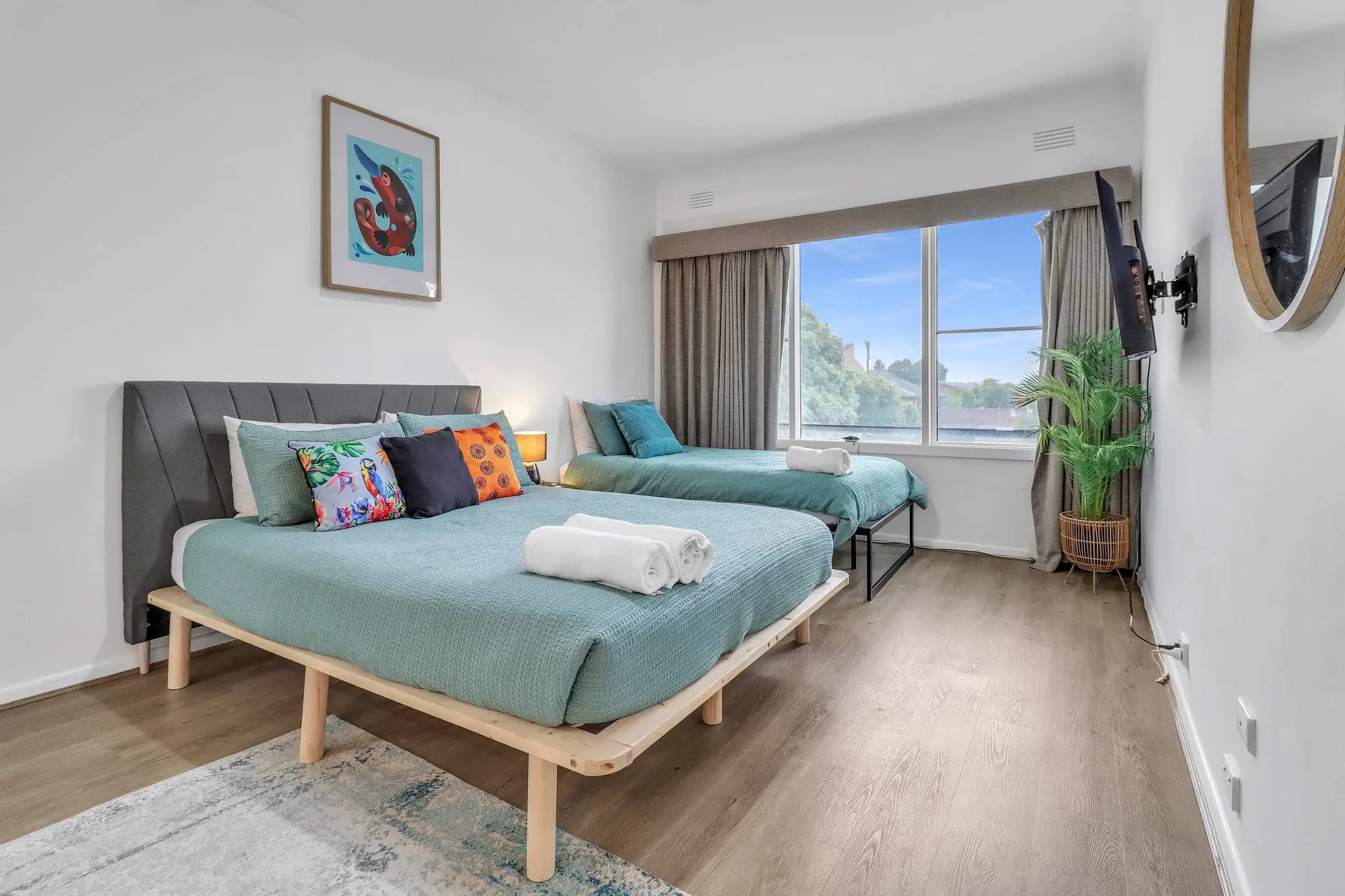 A bedroom with two beds, a large window, and a TV.