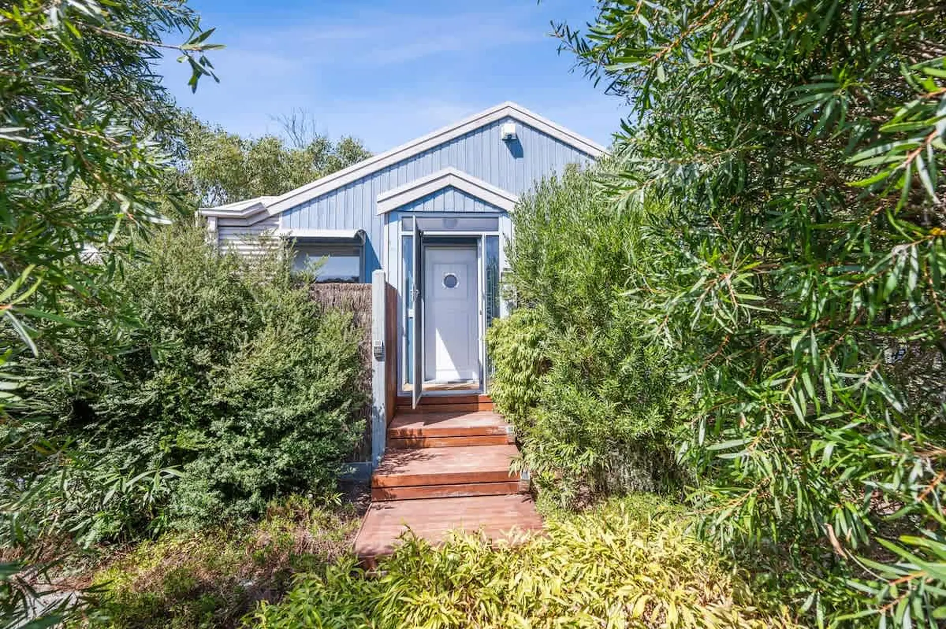 A blue house with a white roof and a glass front door.