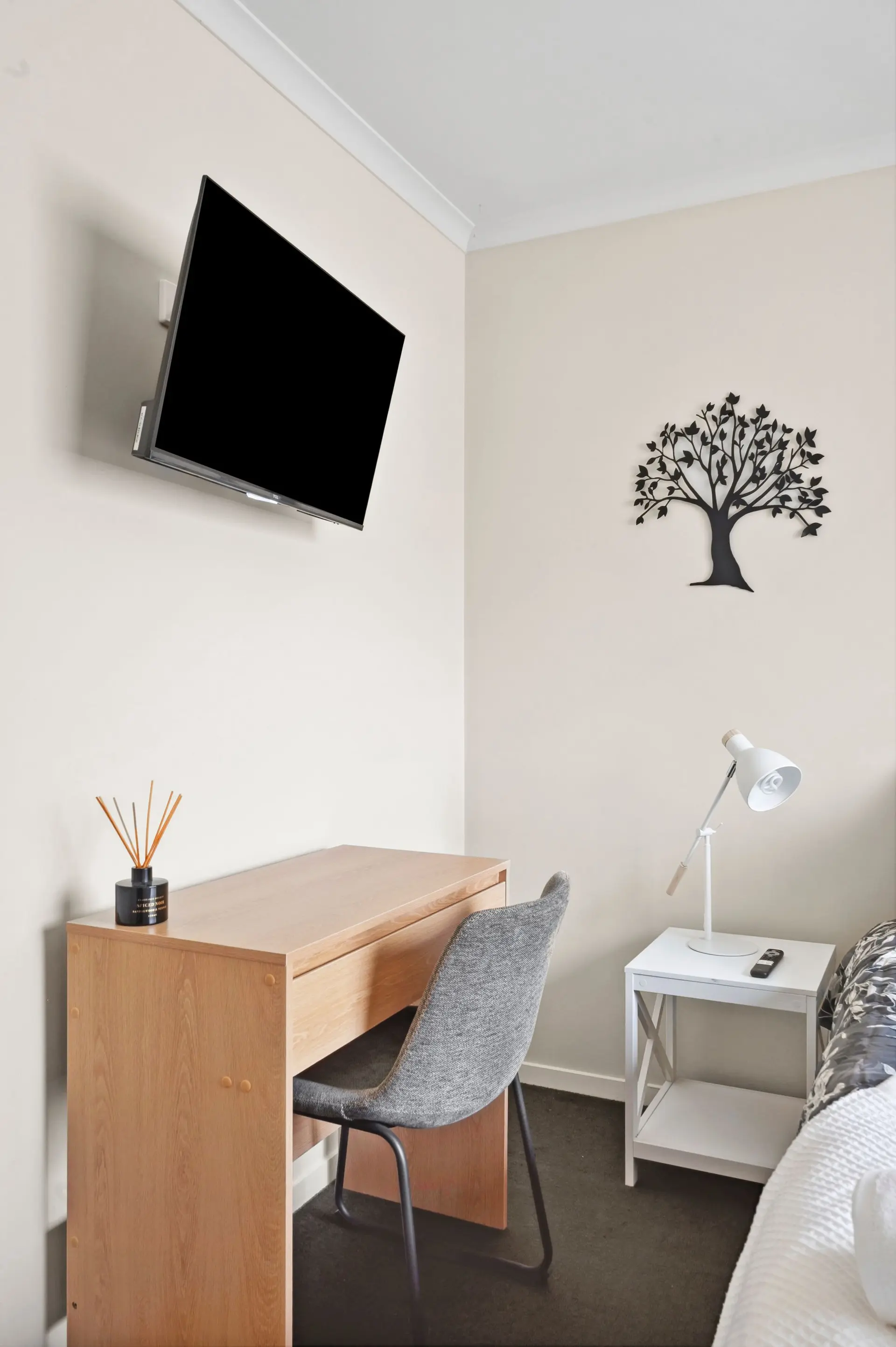 A desk with a diffuser, chair, and TV are in a corner of a room.
