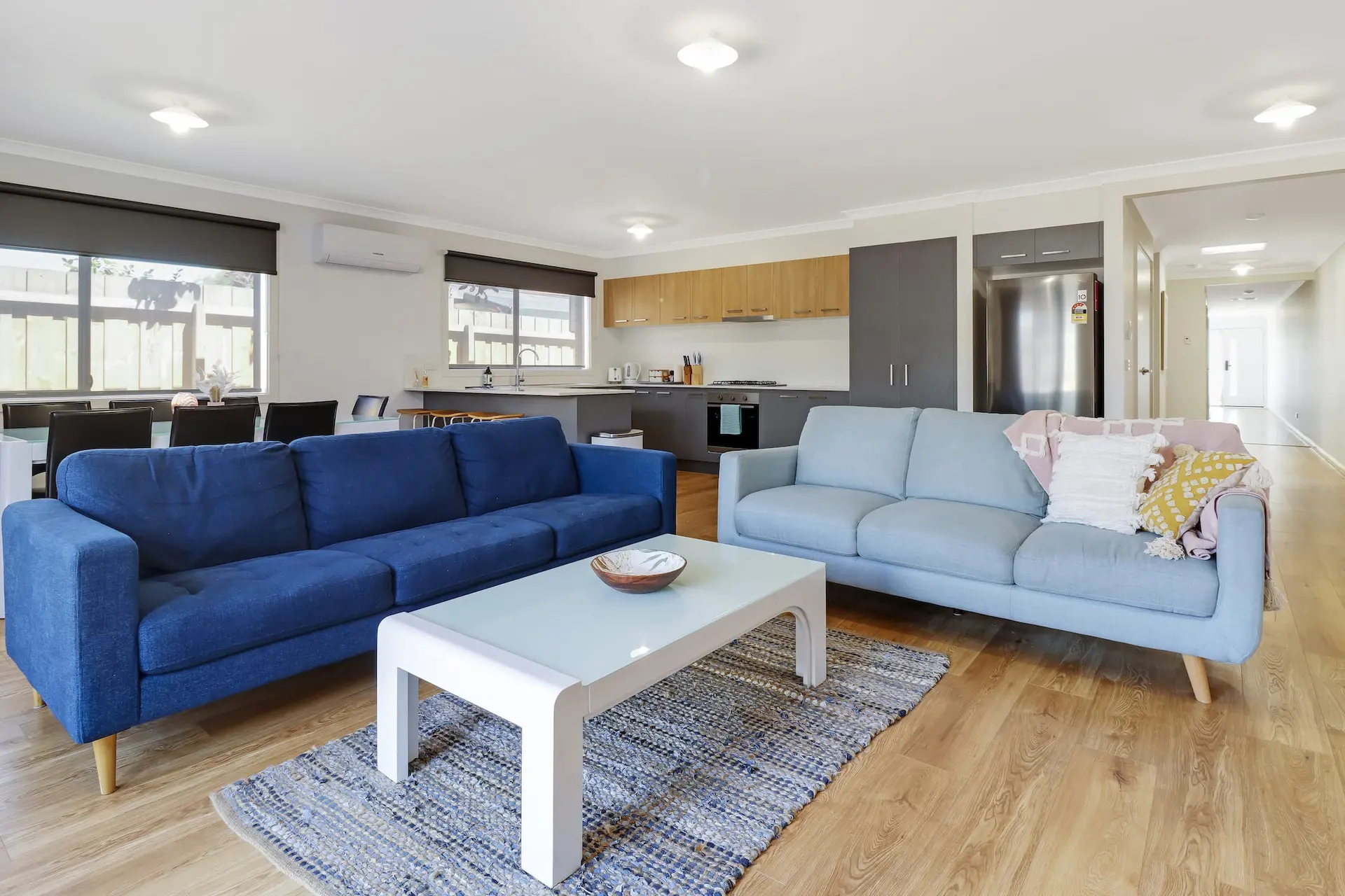 A living room with two sofas, a coffee table, and a rug on a wooden floor.