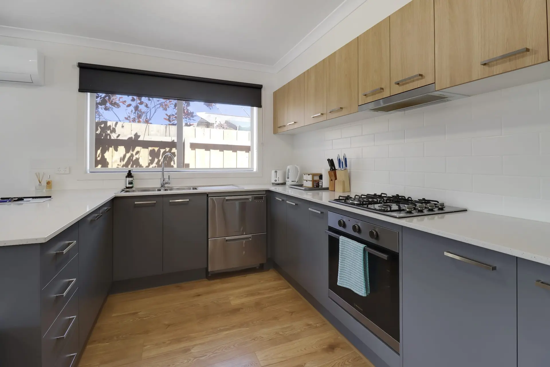 Modern kitchen with gray cabinets, white subway tile backsplash, and light wood upper cabinets.