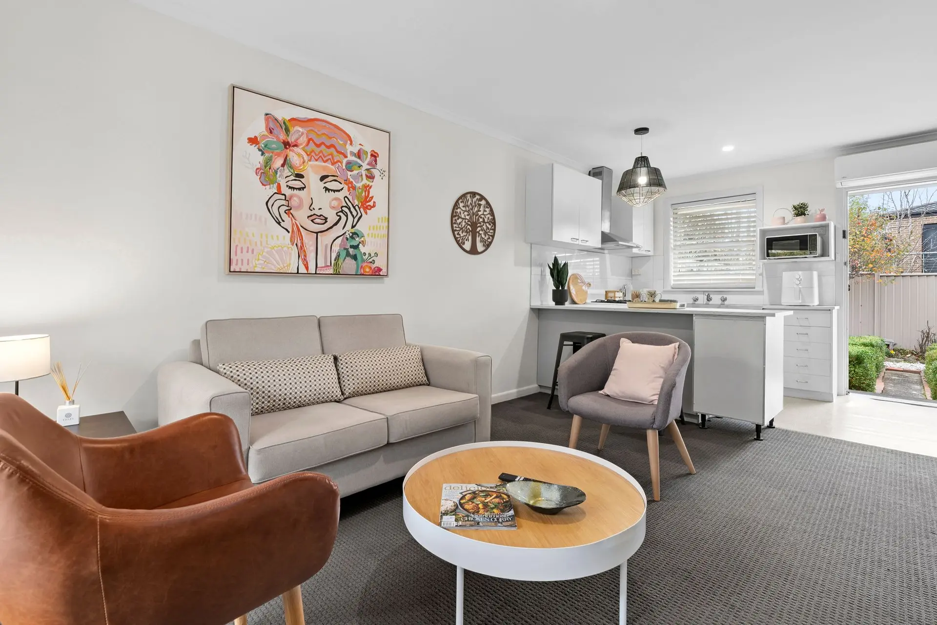 Living room with sofa, chairs, coffee table, and kitchen area.