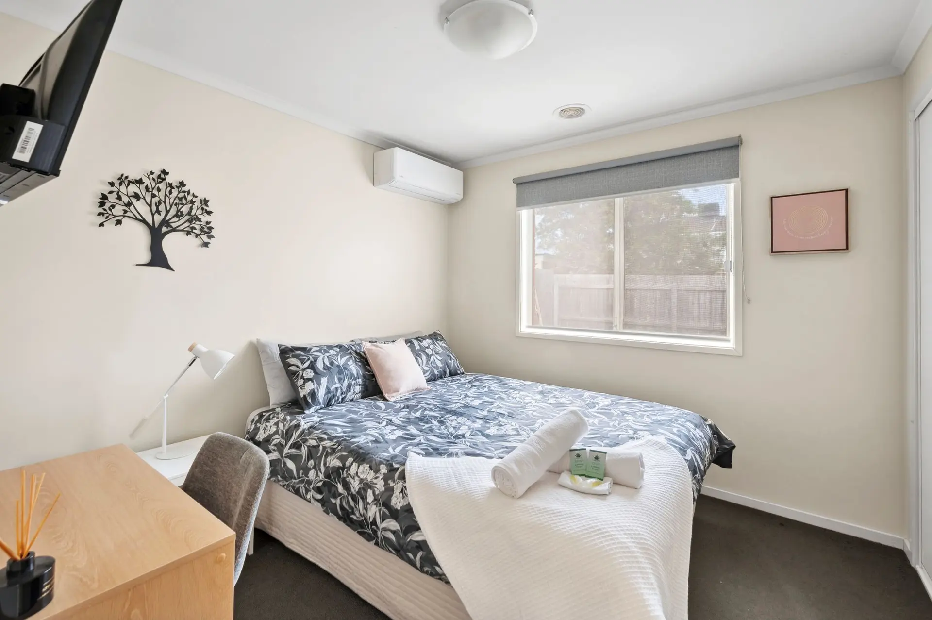 A cozy bedroom with a bed, desk, and a window.