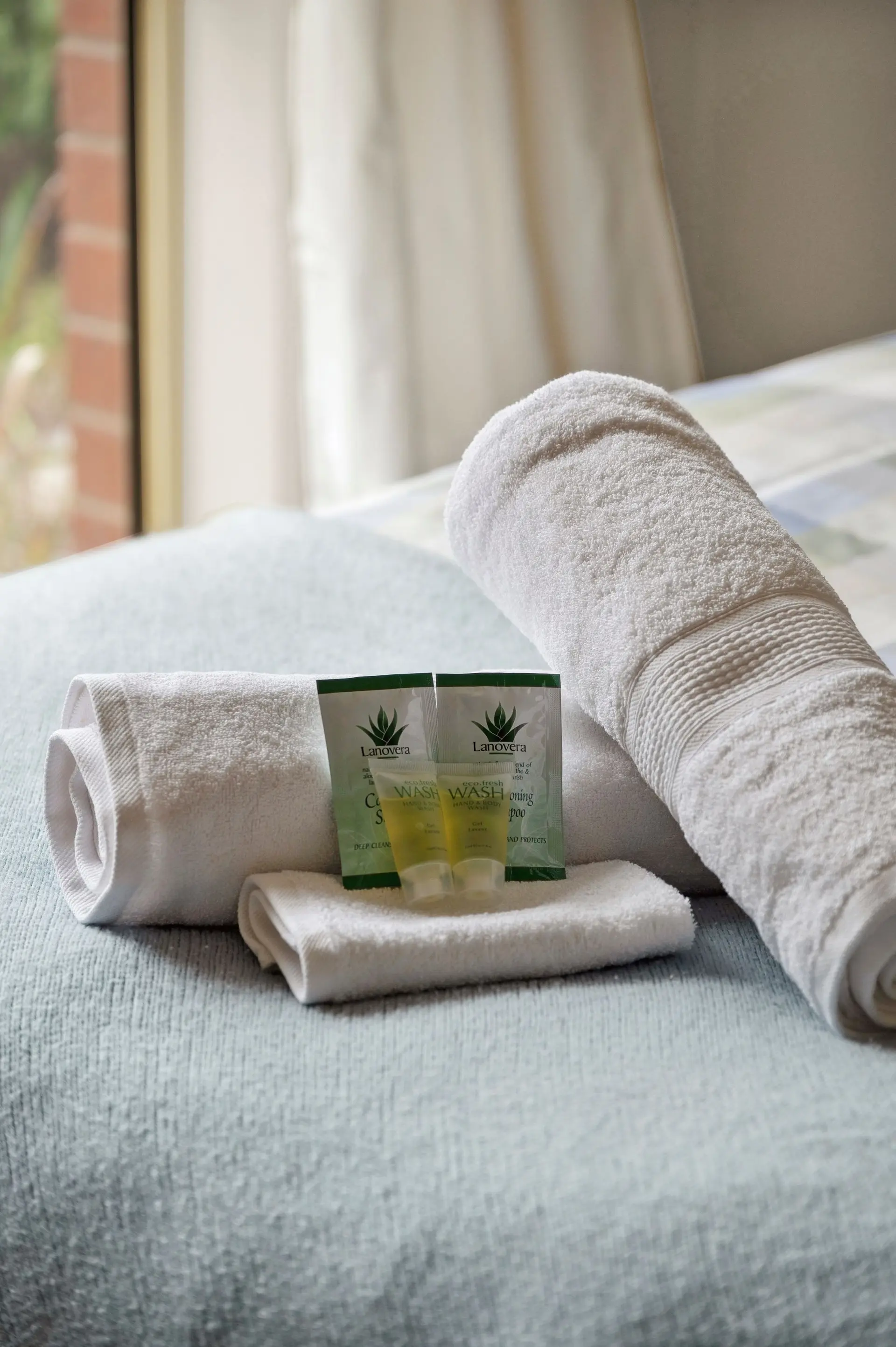 Two rolled white towels and two small bottles of eco-friendly wash with Lanovera branding.