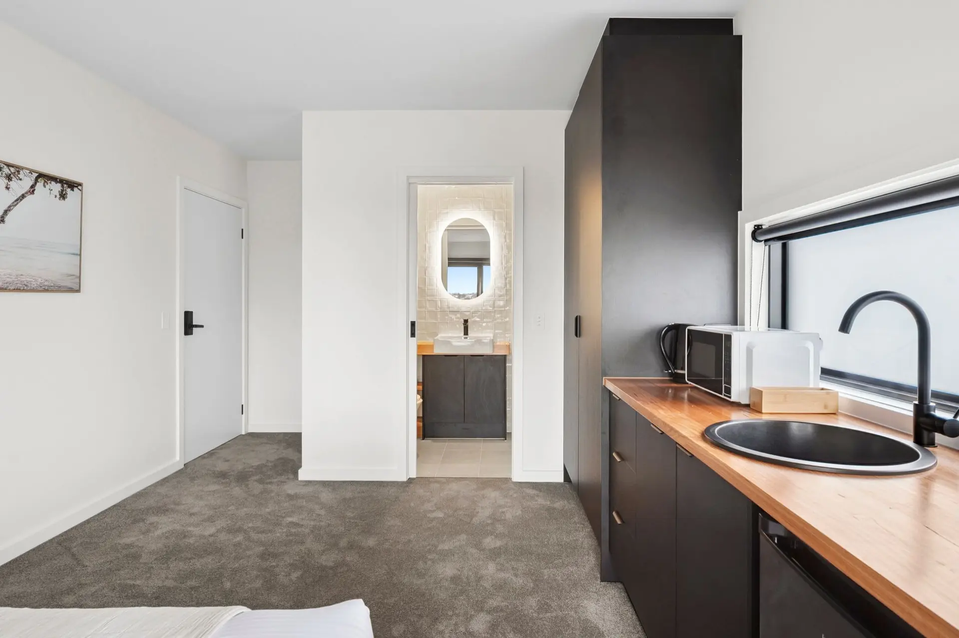 Modern studio apartment with kitchenette, sink, microwave, and bathroom access.