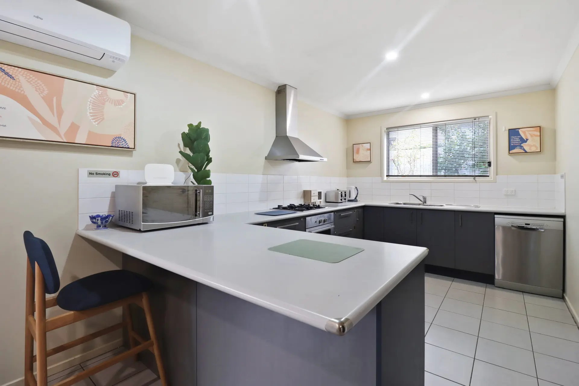 A modern kitchen with dark cabinets, a white countertop, and a stainless steel dishwasher.