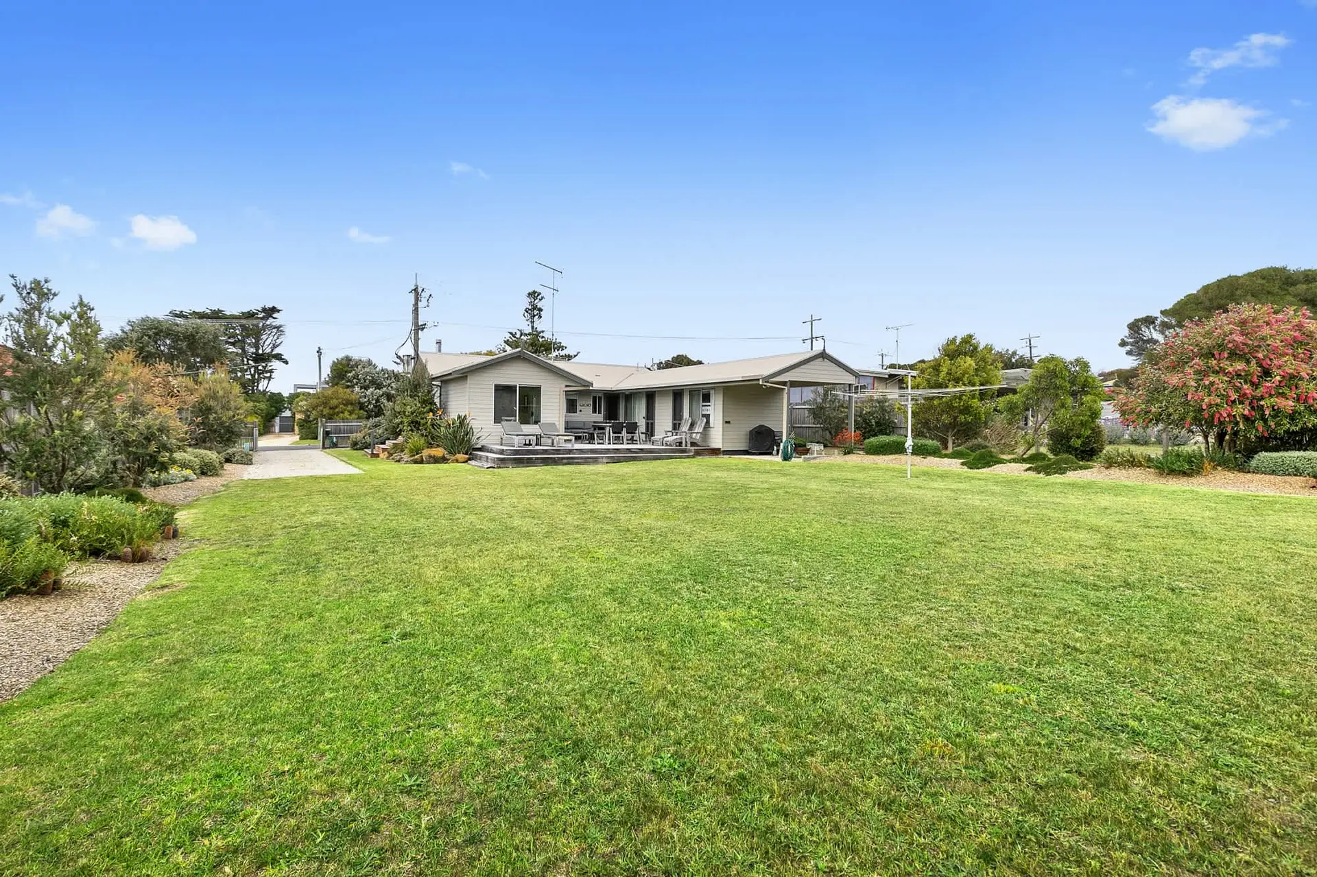 A large, well-maintained backyard with a modern house and trees.