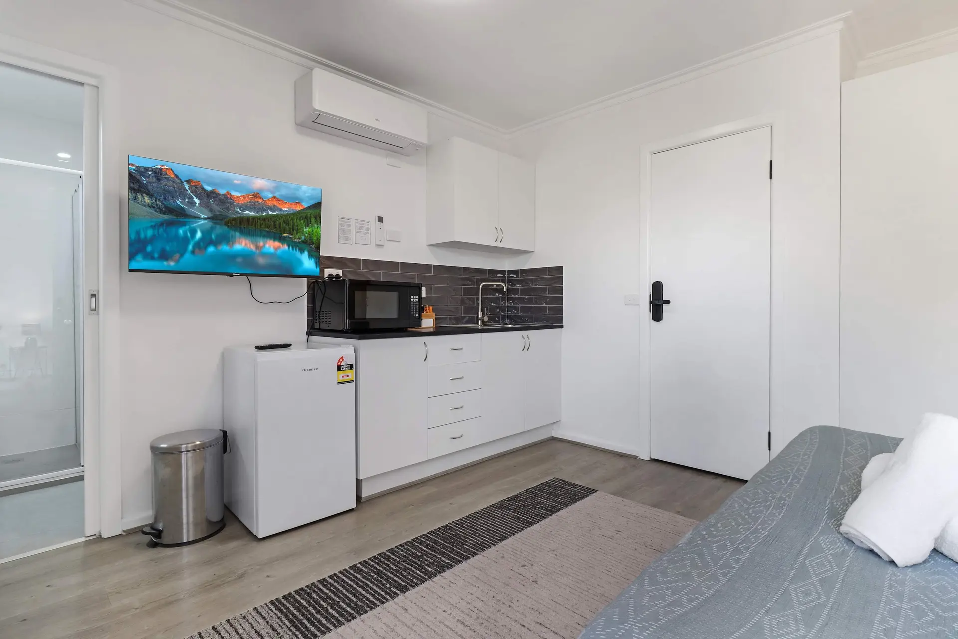 A studio apartment with a kitchenette, refrigerator, microwave, and TV.