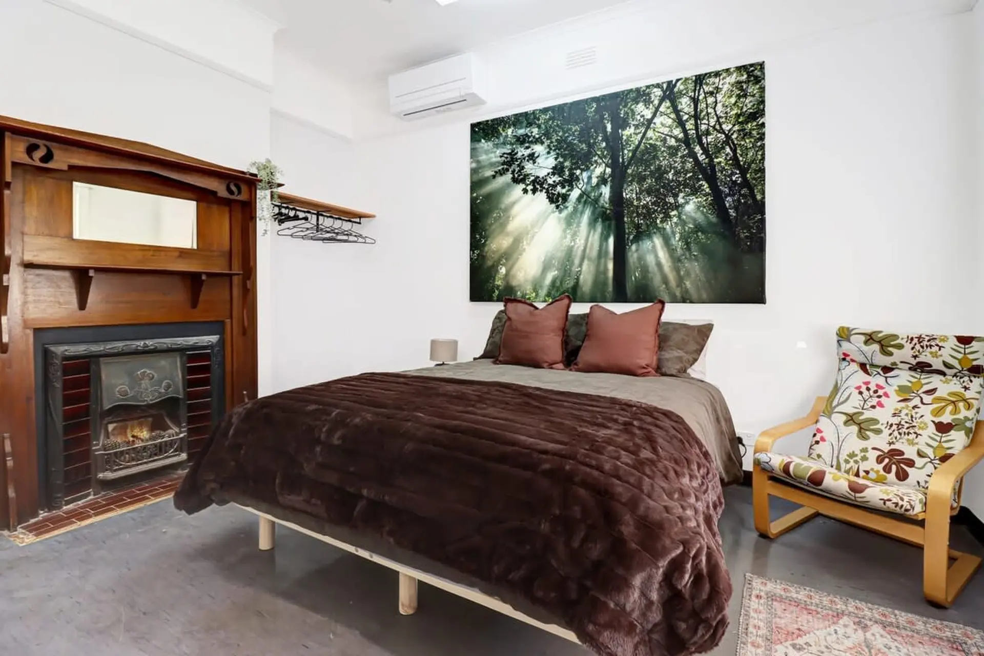 A bedroom with a bed, fireplace, and a chair.