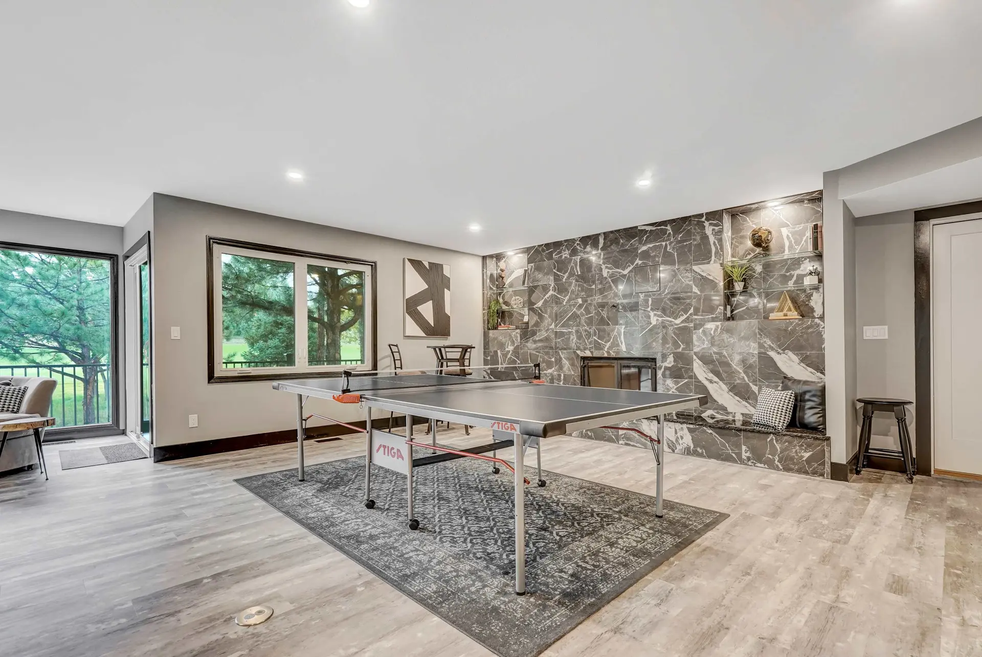Modern recreation room with ping pong table, marble feature wall, and large windows looking out to t