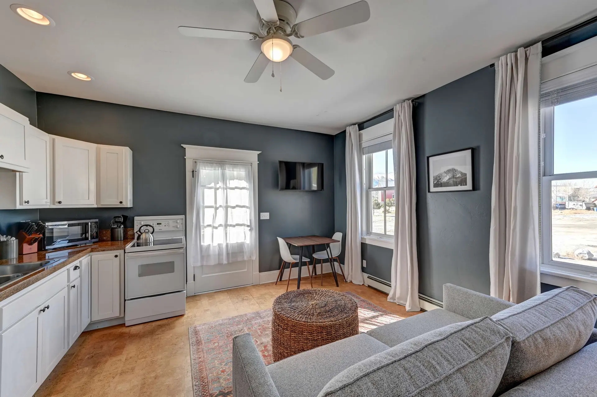 A cozy living room and kitchen area with a couch, coffee table, and small dining set.