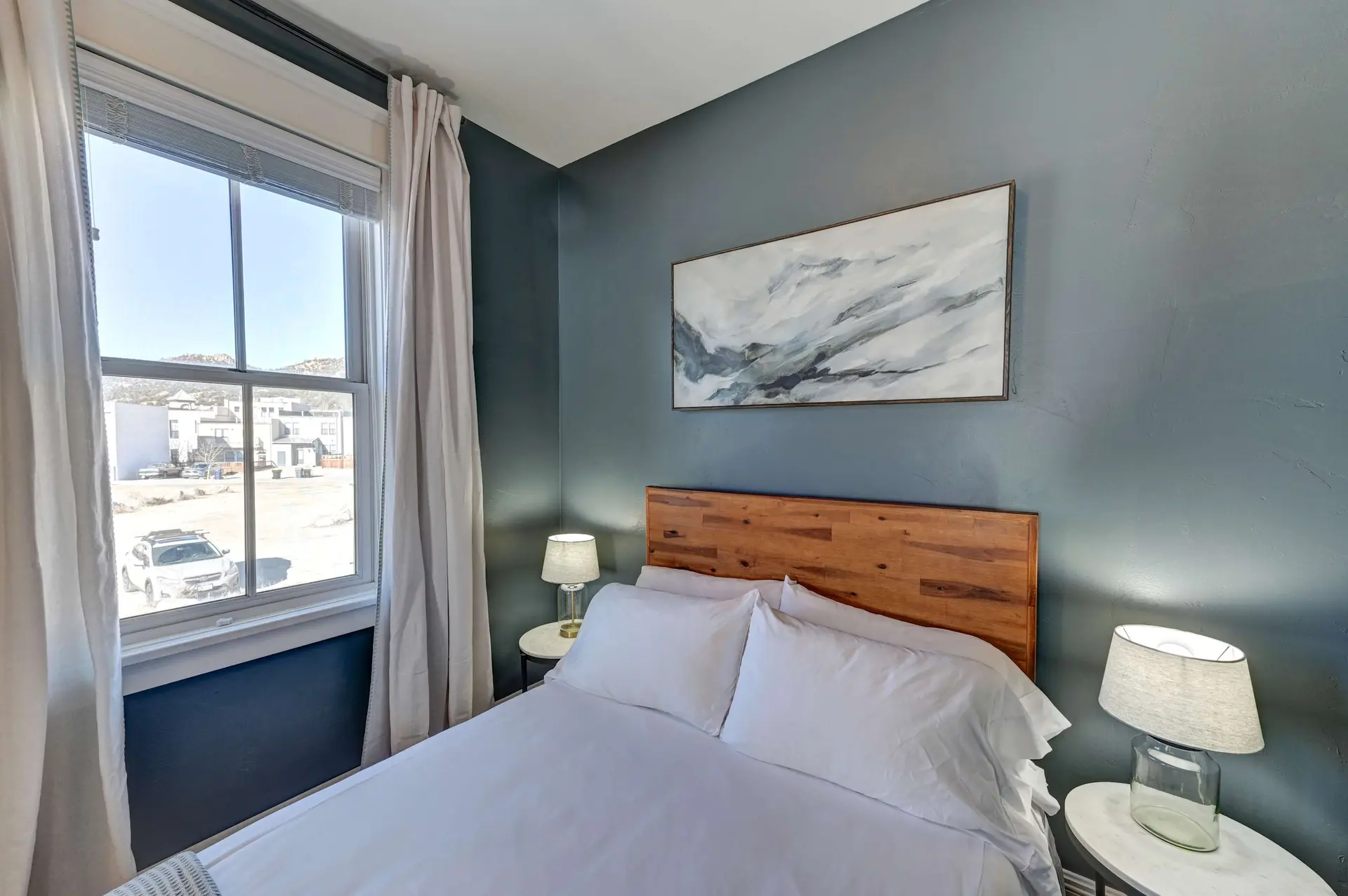 A bedroom with a white bed and a wooden headboard.