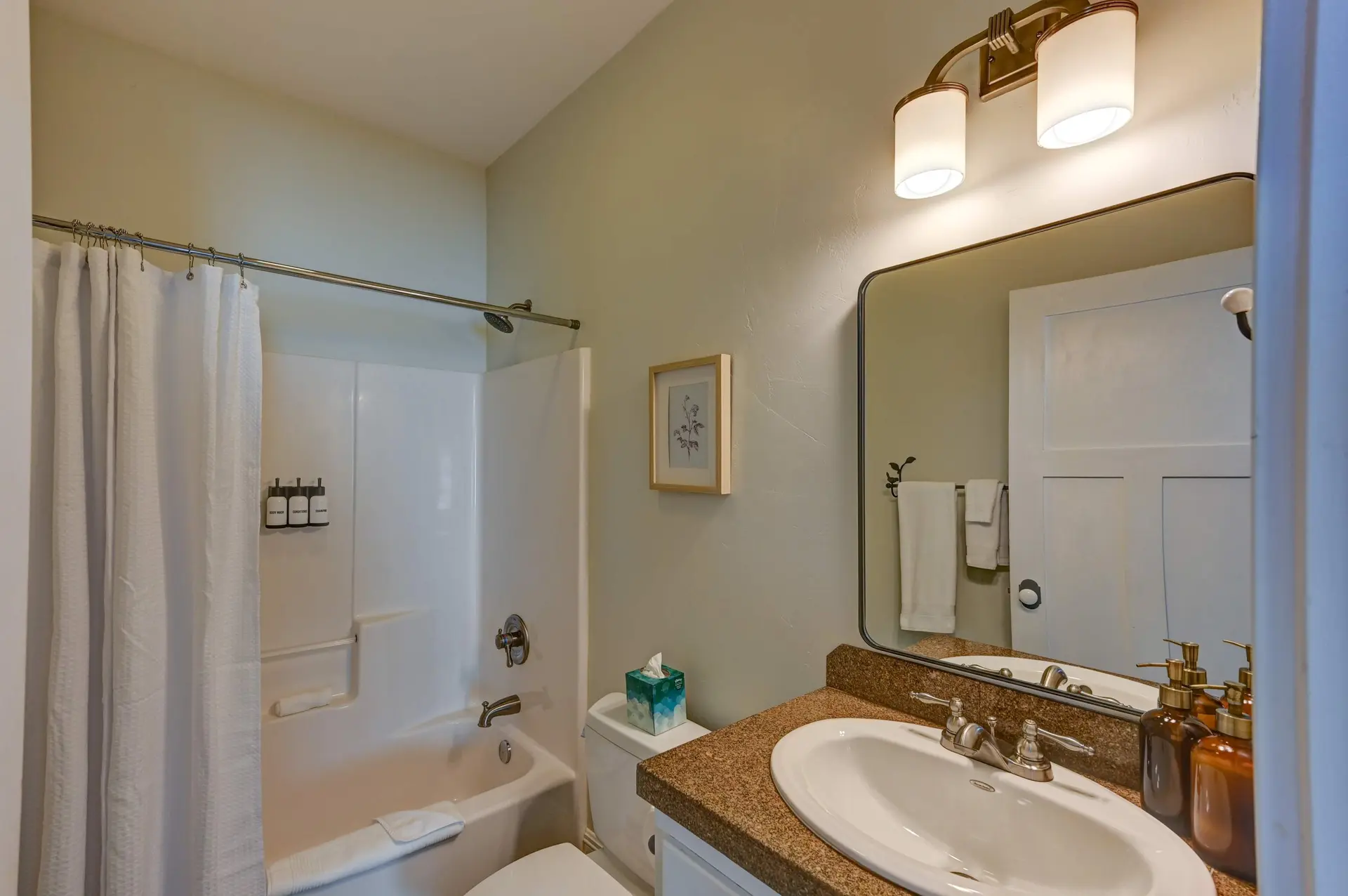 Bathroom with shower, toilet, sink, and mirror.