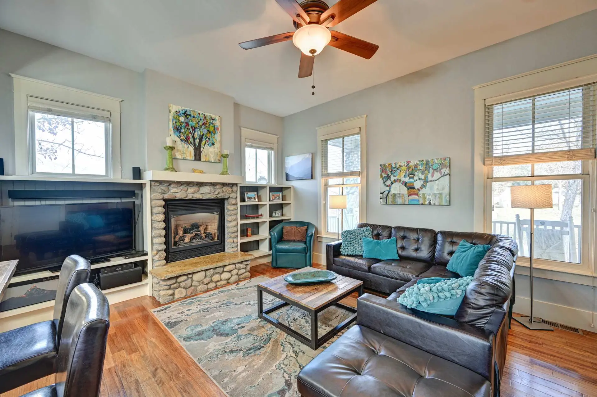 Living room with a fireplace, sectional sofa, coffee table, and ceiling fan.