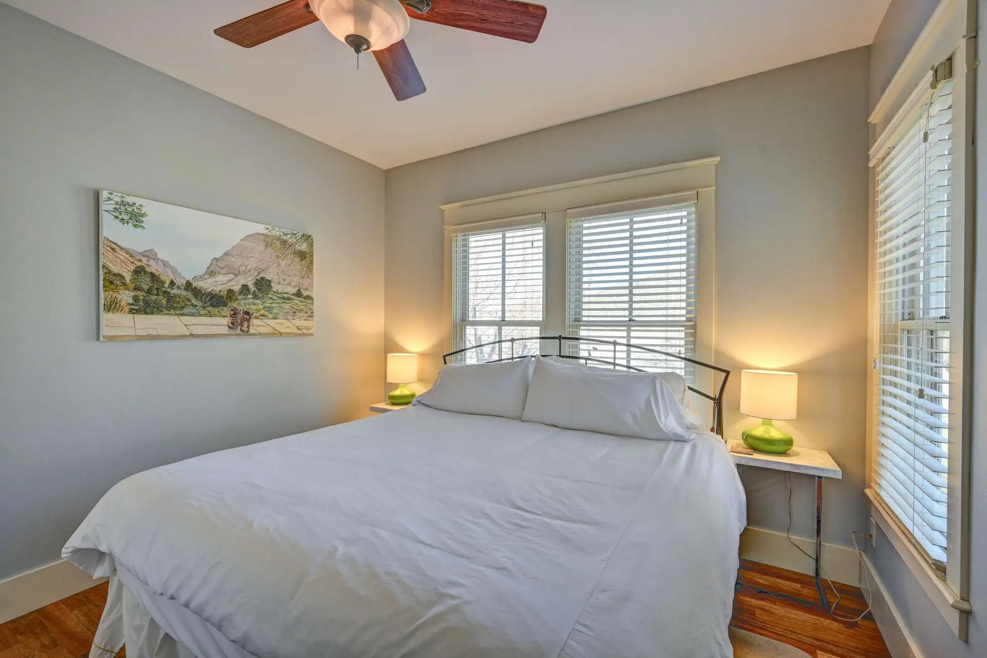 A bed with white linens sits in a bedroom with pale grey walls.
