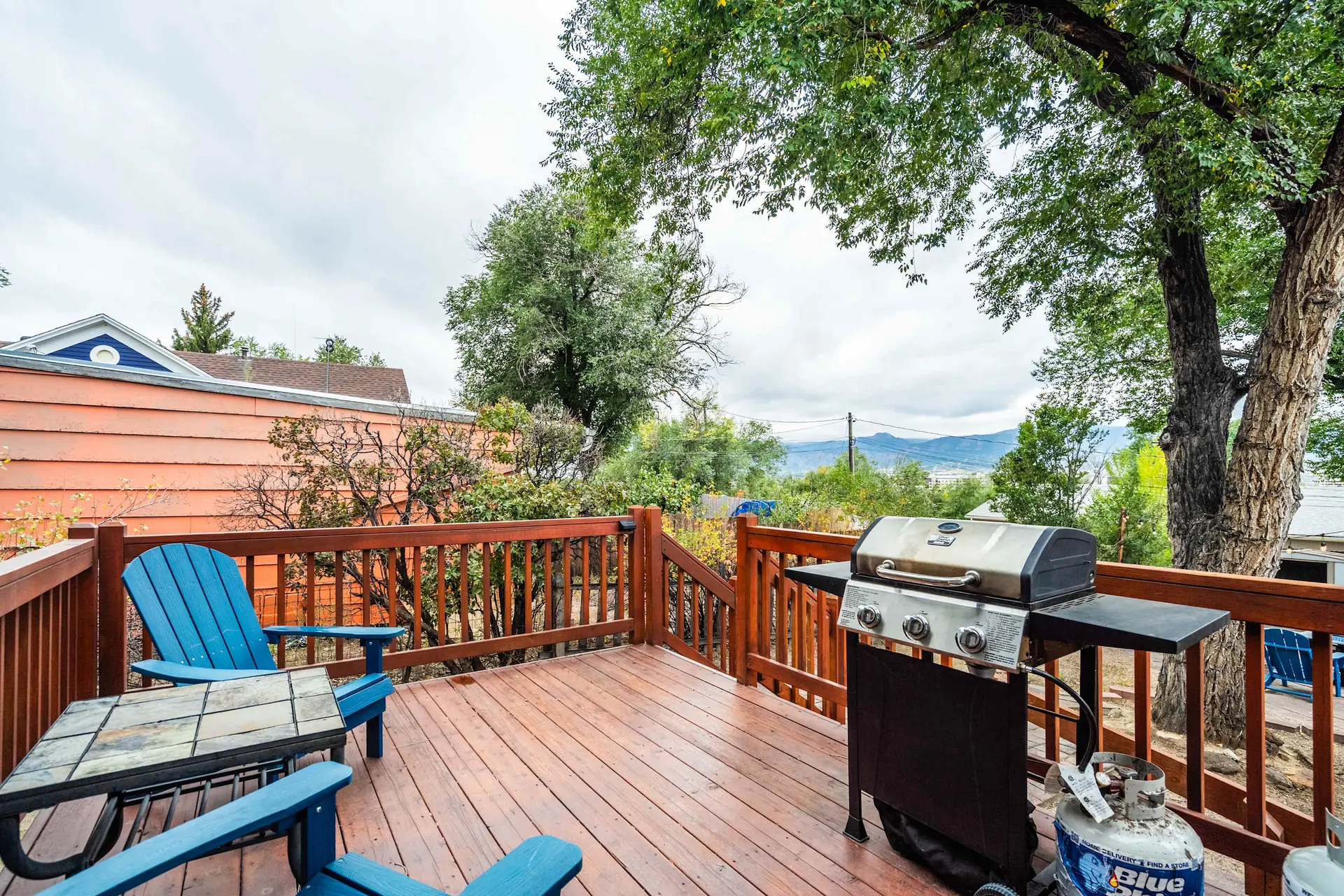 Outdoor deck with grill, chairs, table, and a distant mountain view.