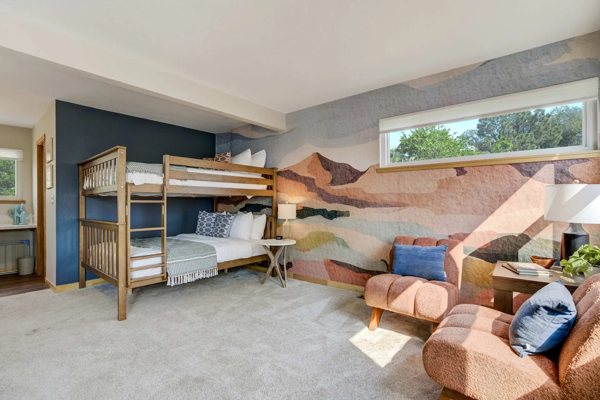 A colorful bedroom featuring a bunk bed, a mountain mural, and two orange armchairs.