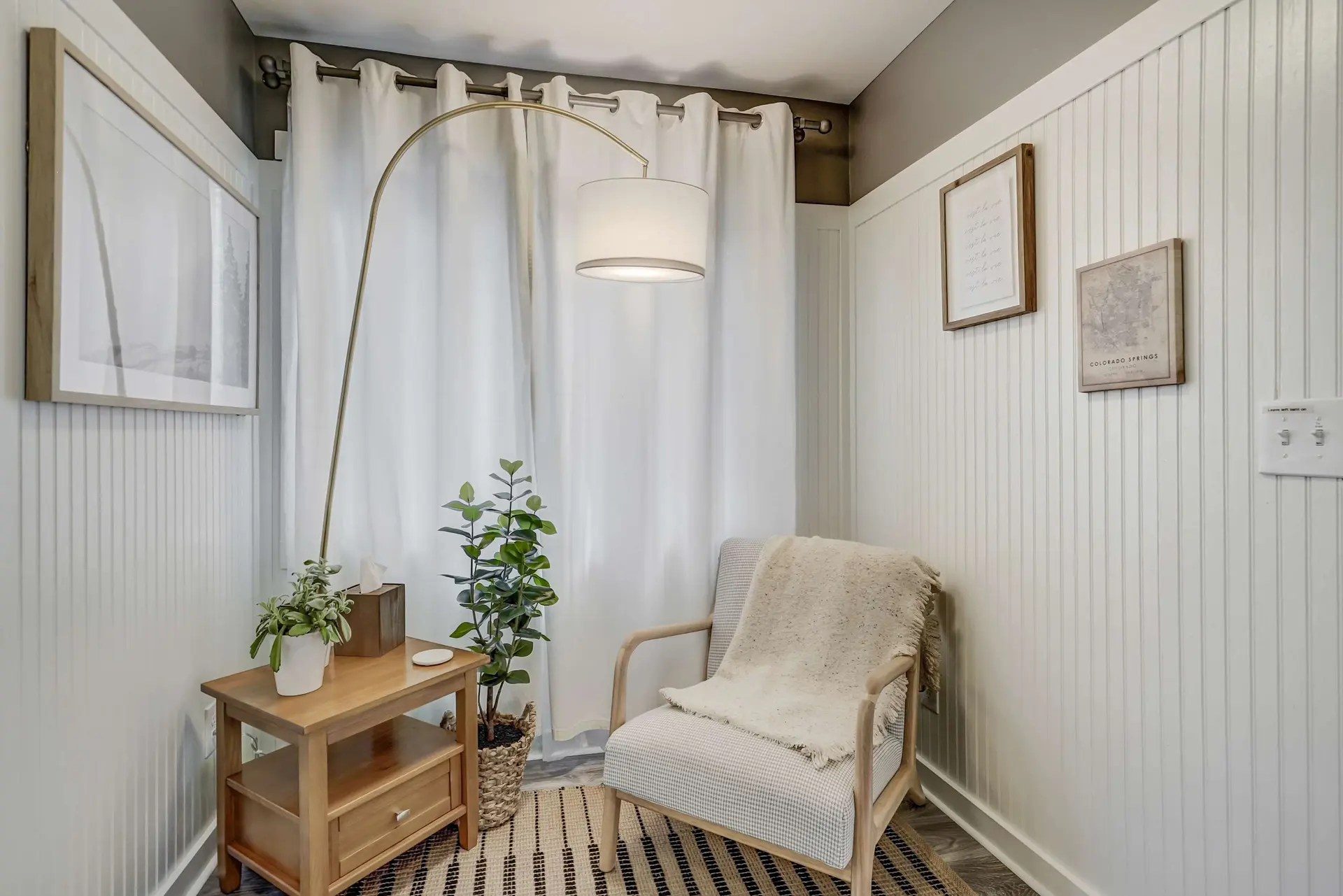 A cozy corner features a chair with a fuzzy blanket, a side table with plants and tissues, and a flo