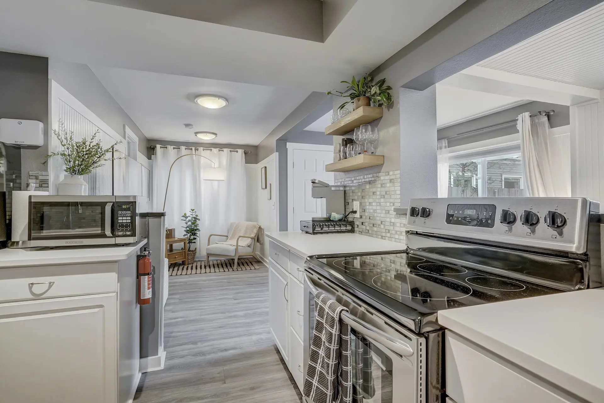 A modern kitchen with white cabinets, a stainless steel stove, and a microwave.
