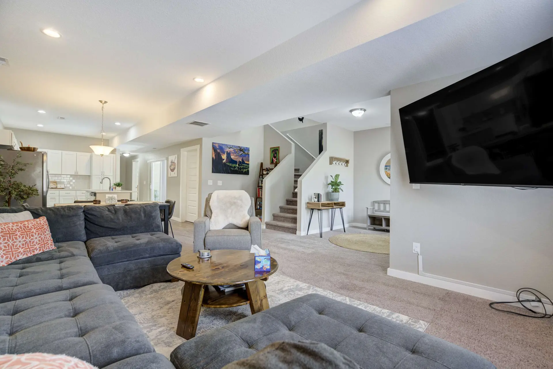 Modern living room with a gray sectional sofa, wooden coffee table, and wall-mounted TV.
