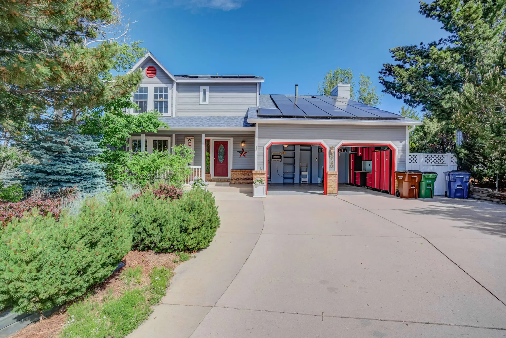 A suburban home with a grey exterior, red front door, and attached two-car garage.