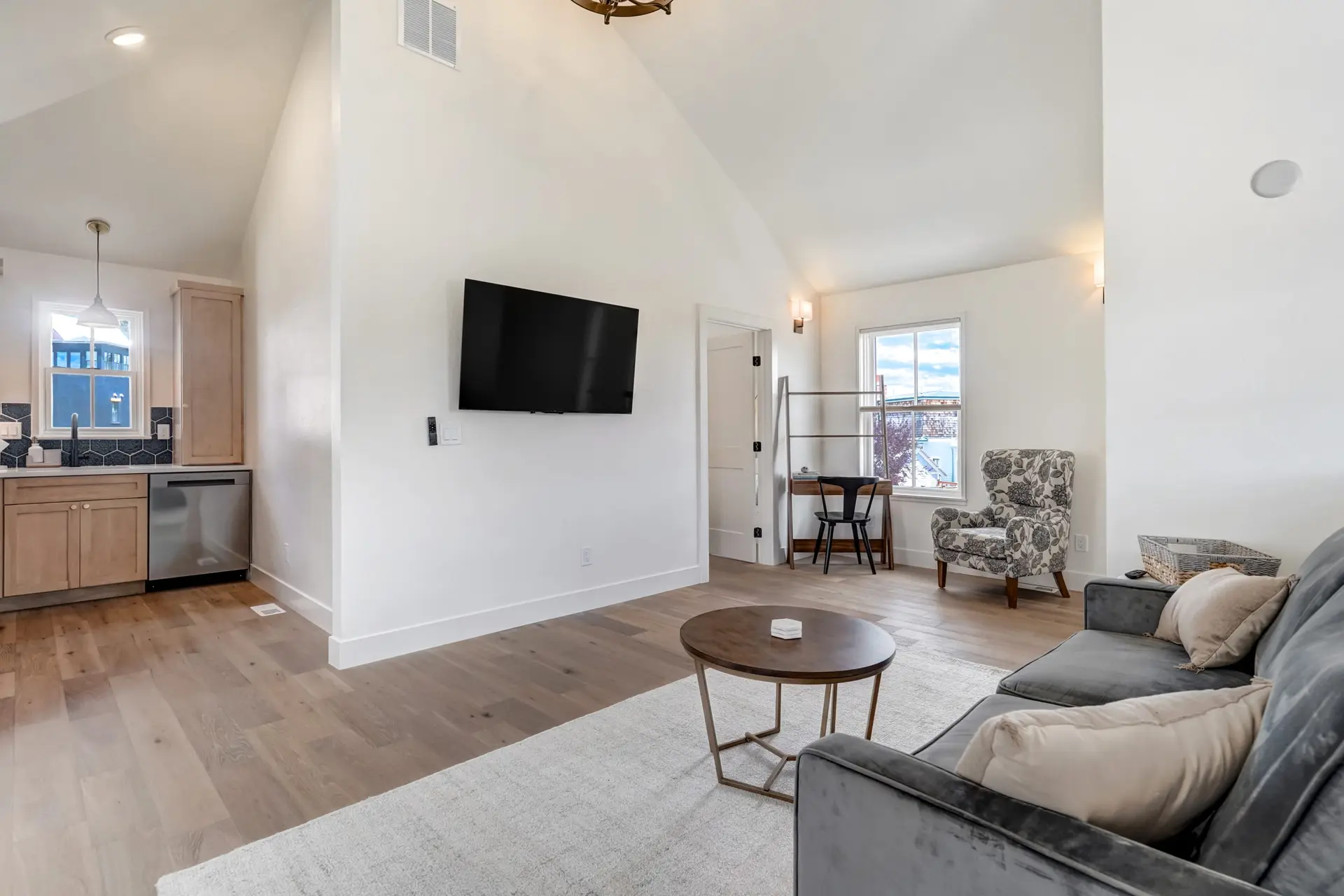 Living room with couch, coffee table, chair, desk, and TV.