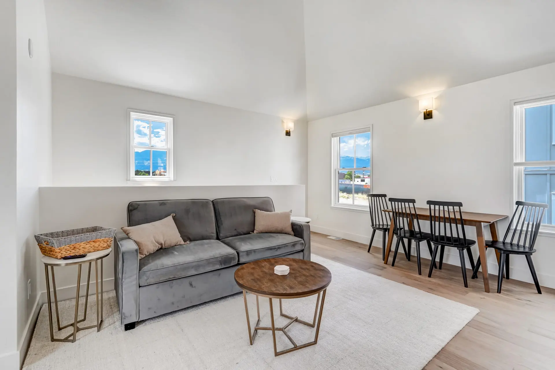 A modern living and dining room with a gray sofa, wood dining table and chairs.