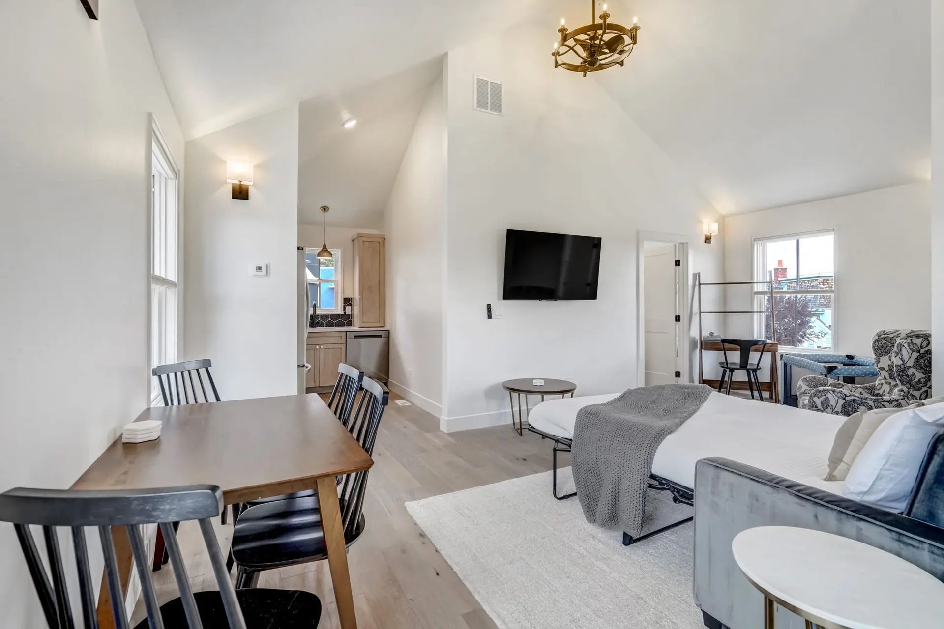 A studio apartment with a kitchenette, dining area, and pull-out sofa bed.