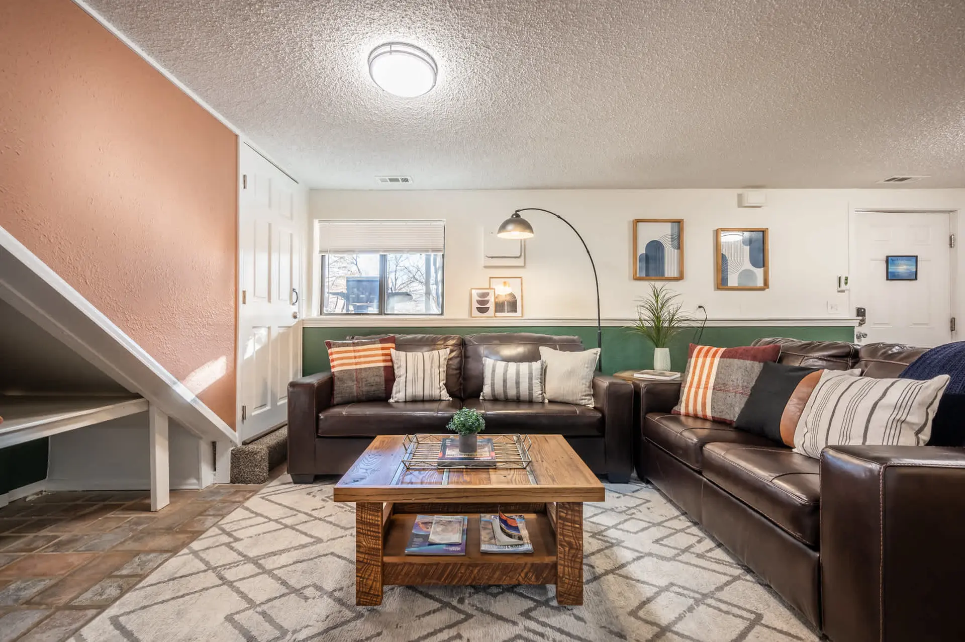 Brown leather sofas and a wooden coffee table are arranged in a living room with a textured ceiling 