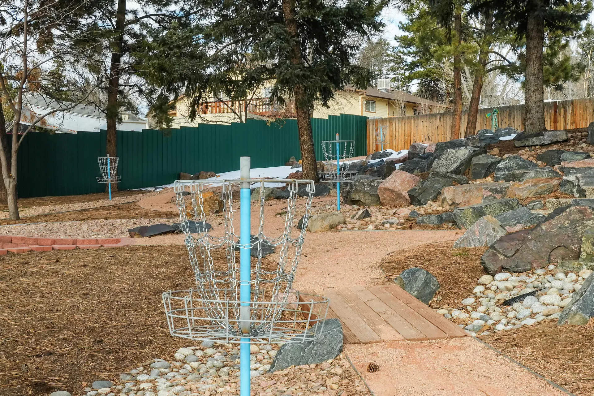 Disc golf course with chains, baskets, rocks, and a wooden bridge.