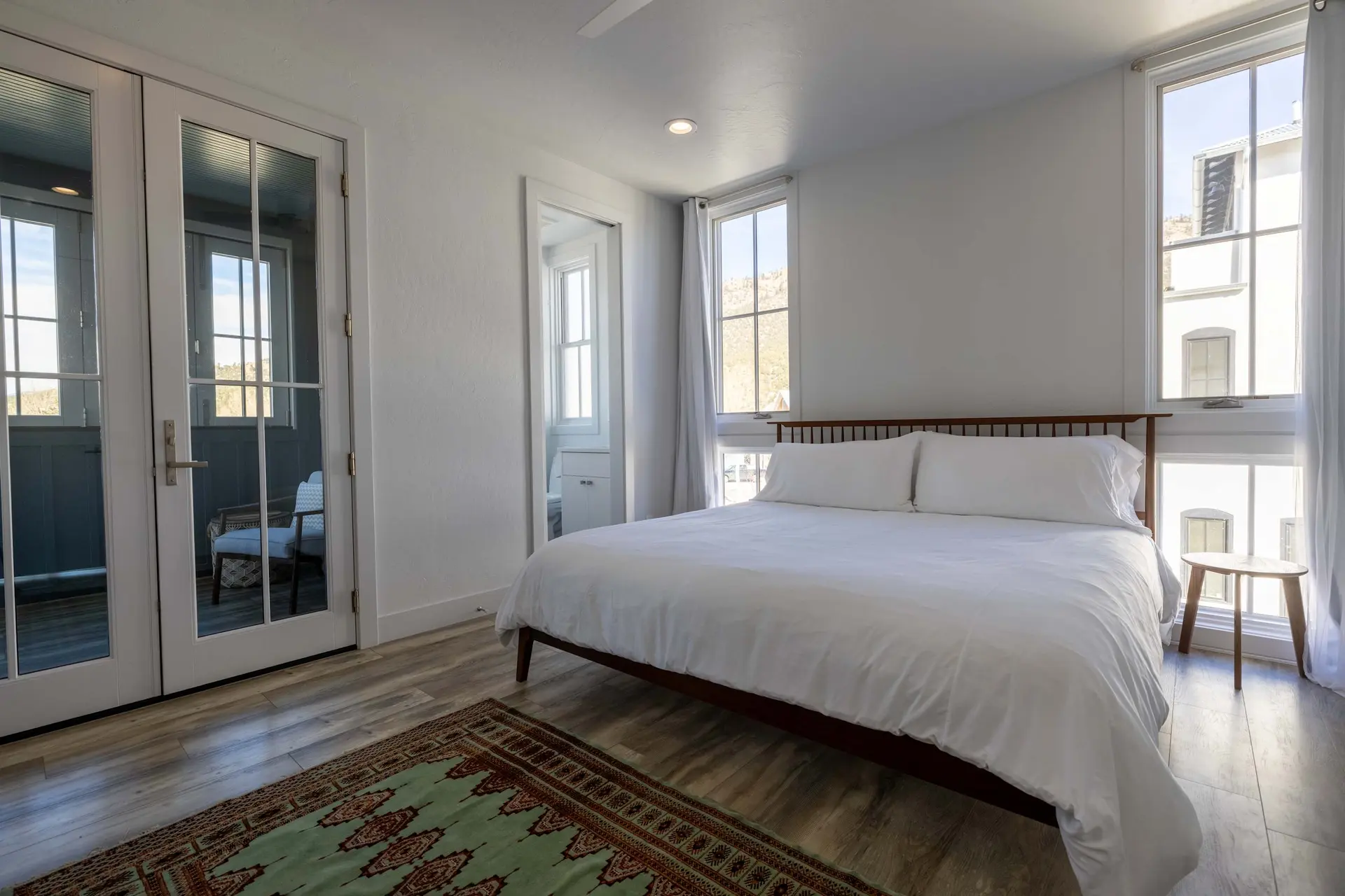 A white king-size bed with white linens in a bright bedroom.