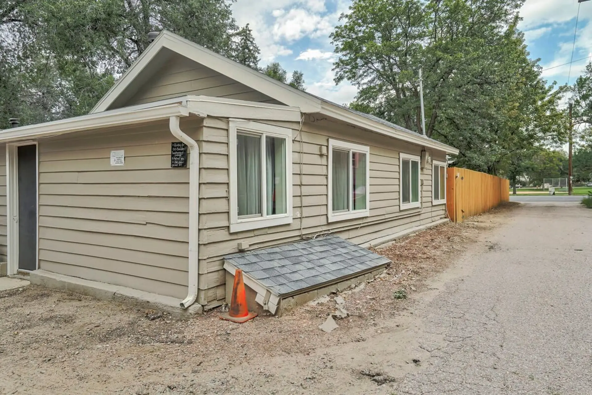 A tan-sided building with white-trimmed windows and a wooden fence.