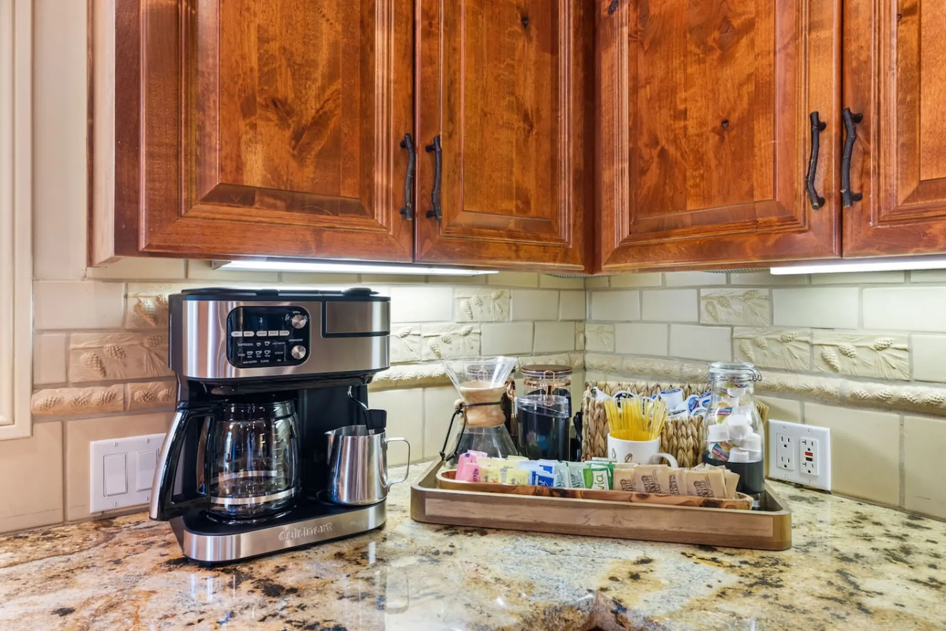 Coffee maker with coffee pods, sugar, and tea on a granite countertop.
