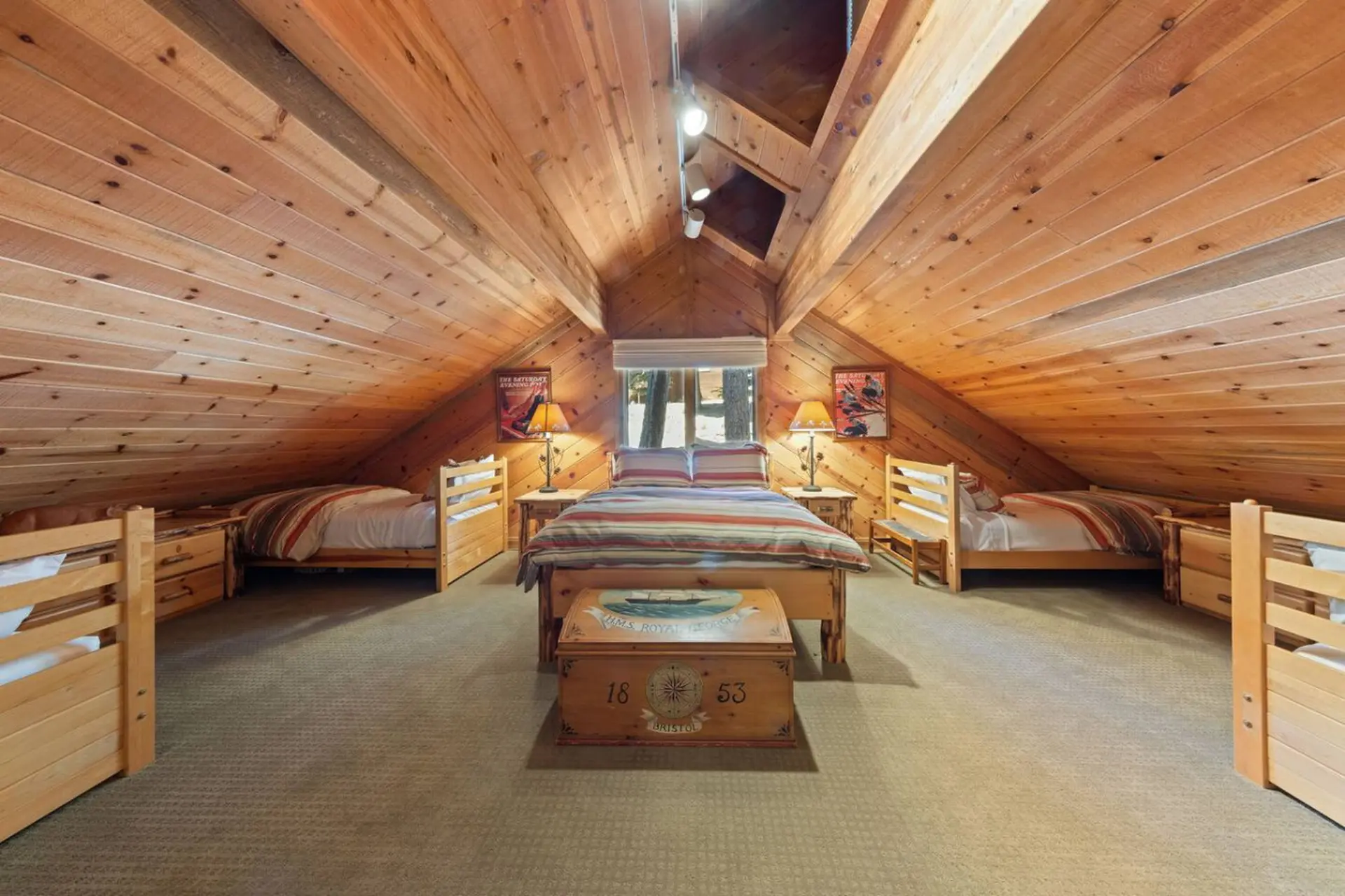 Attic bedroom with wood-paneled walls and slanted ceiling, featuring four twin beds and a decorative