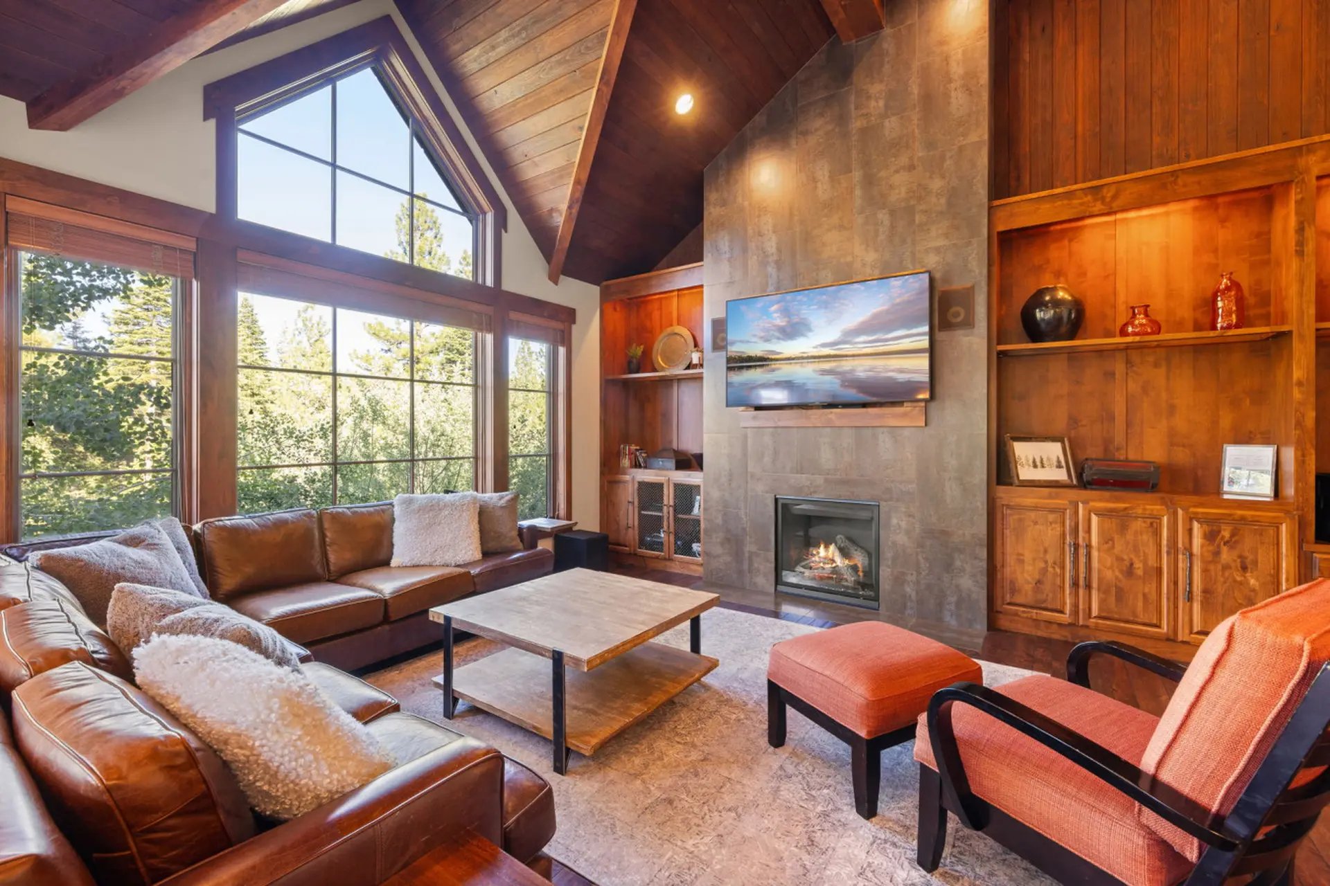 A cozy living room with a large leather sectional, a fireplace, and a scenic view.