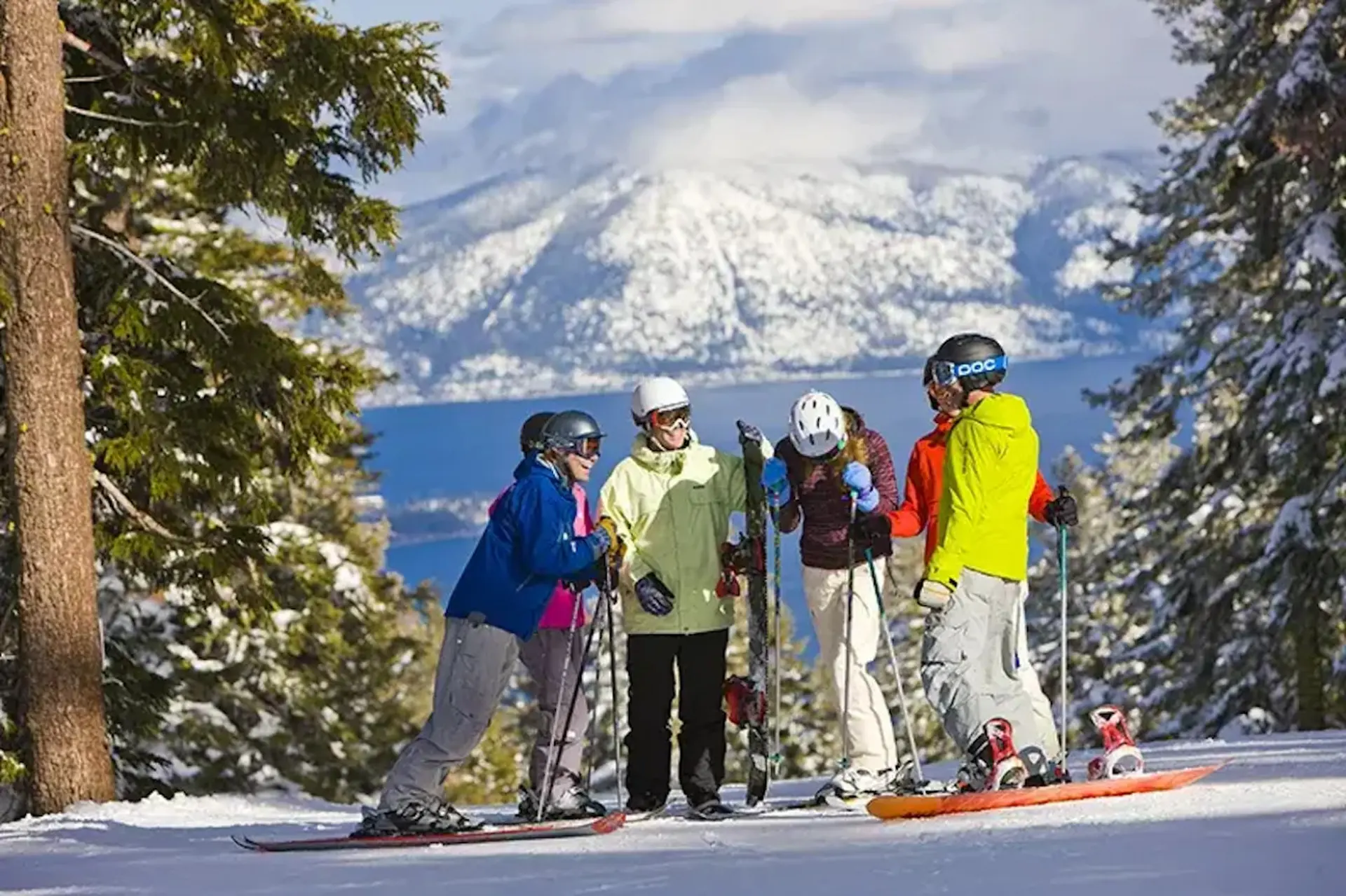 A group of five skiers and snowboarders on a snowy mountain slope.