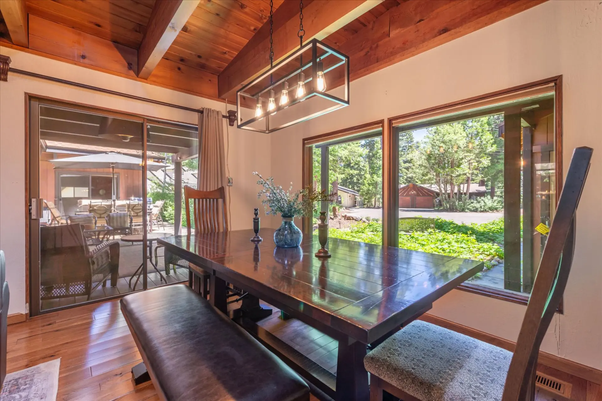 A dining room with a wooden table, bench, chairs, and a view of the outdoors.