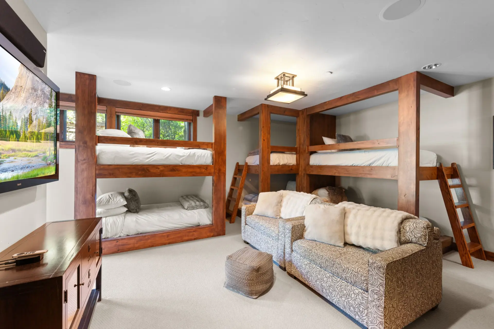 A rustic bedroom with bunk beds, plush seating, and a TV.