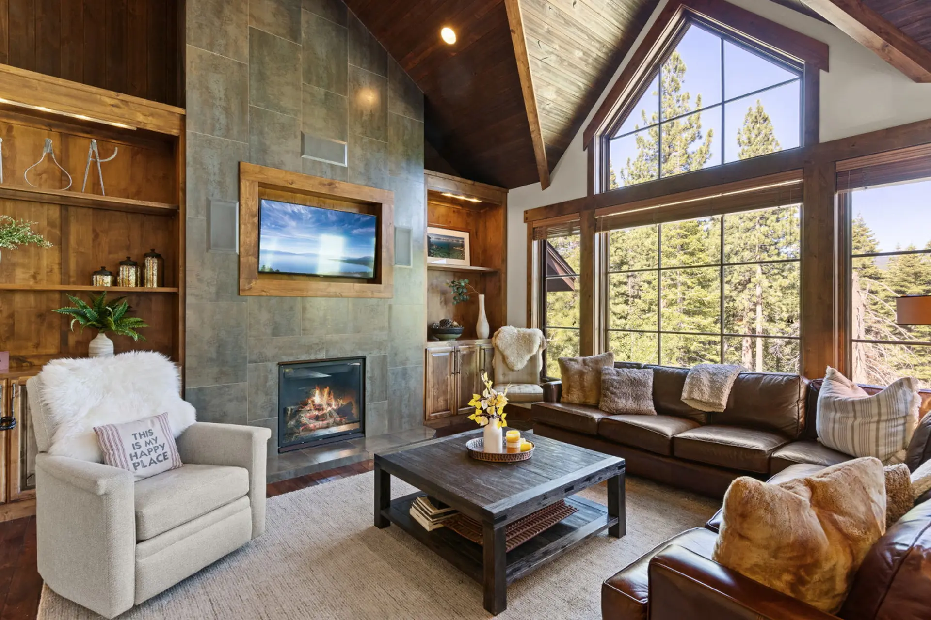 A cozy living room with a fireplace, large windows, and comfortable seating.