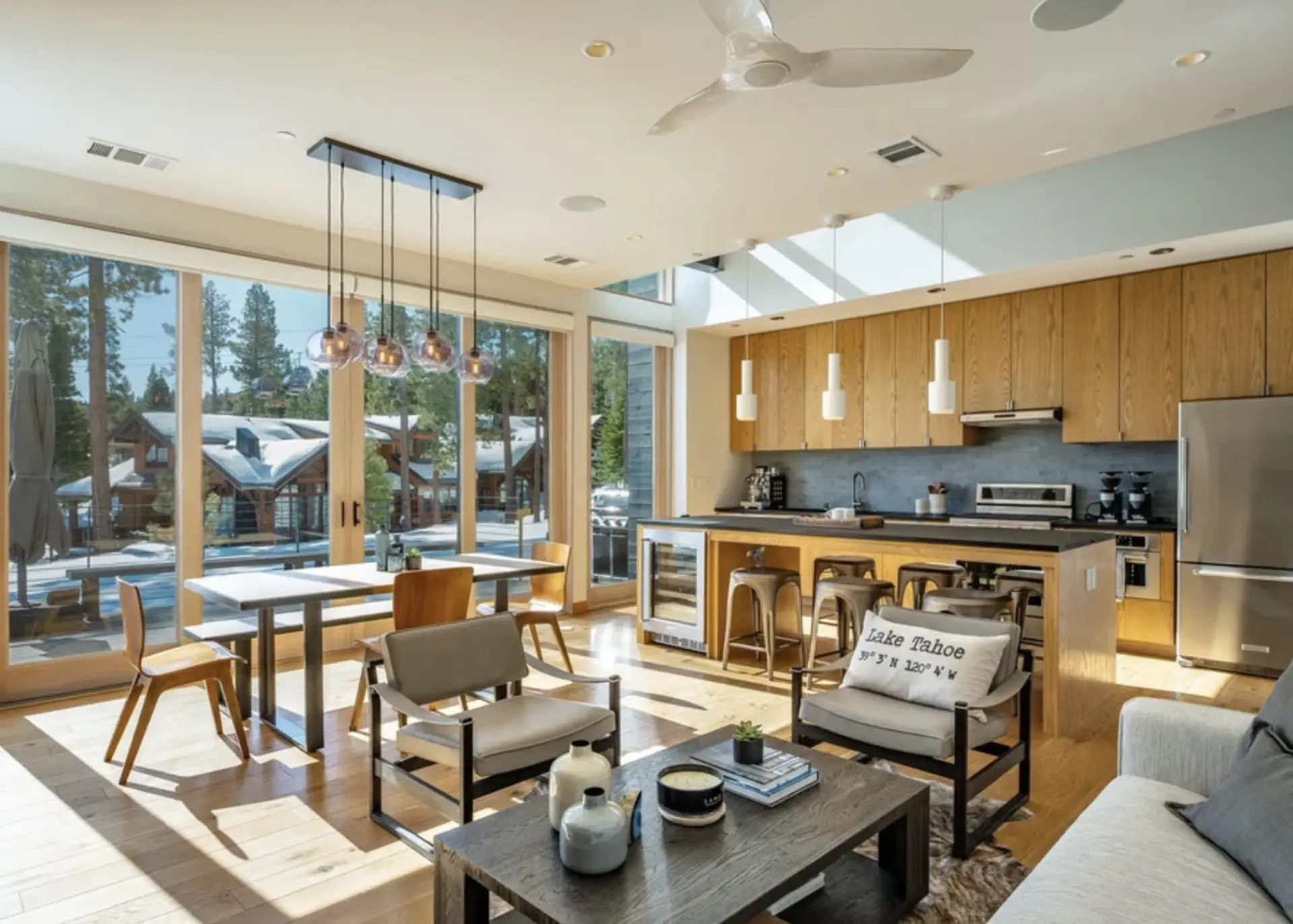 Modern living room and kitchen with large windows overlooking a snowy landscape.