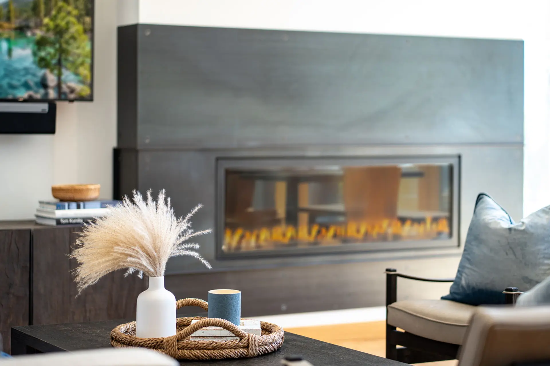 Modern living room with a fireplace, a TV, and a coffee table with a vase of pampas grass.