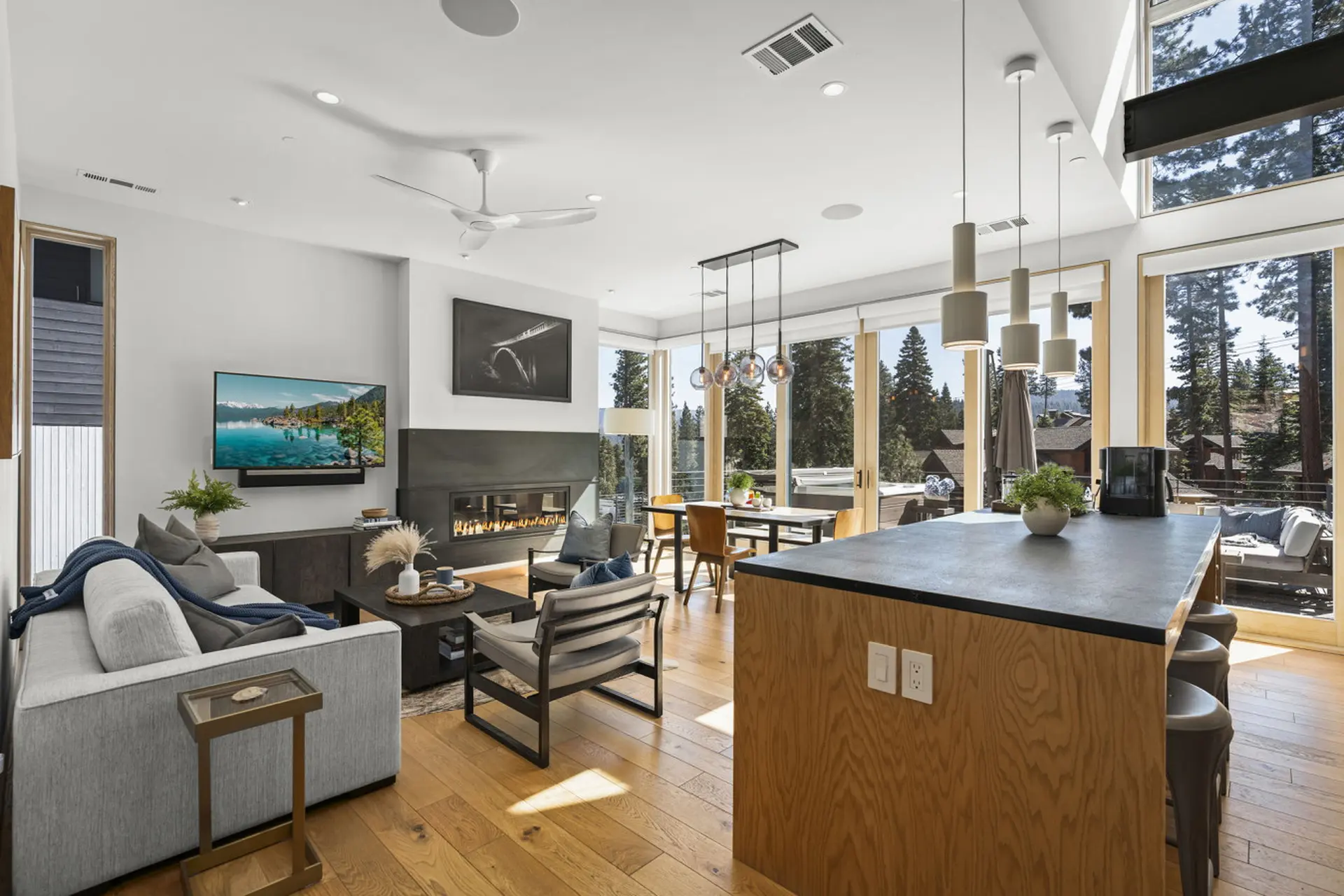 A modern living room with a fireplace, TV, dining area, and kitchen island.
