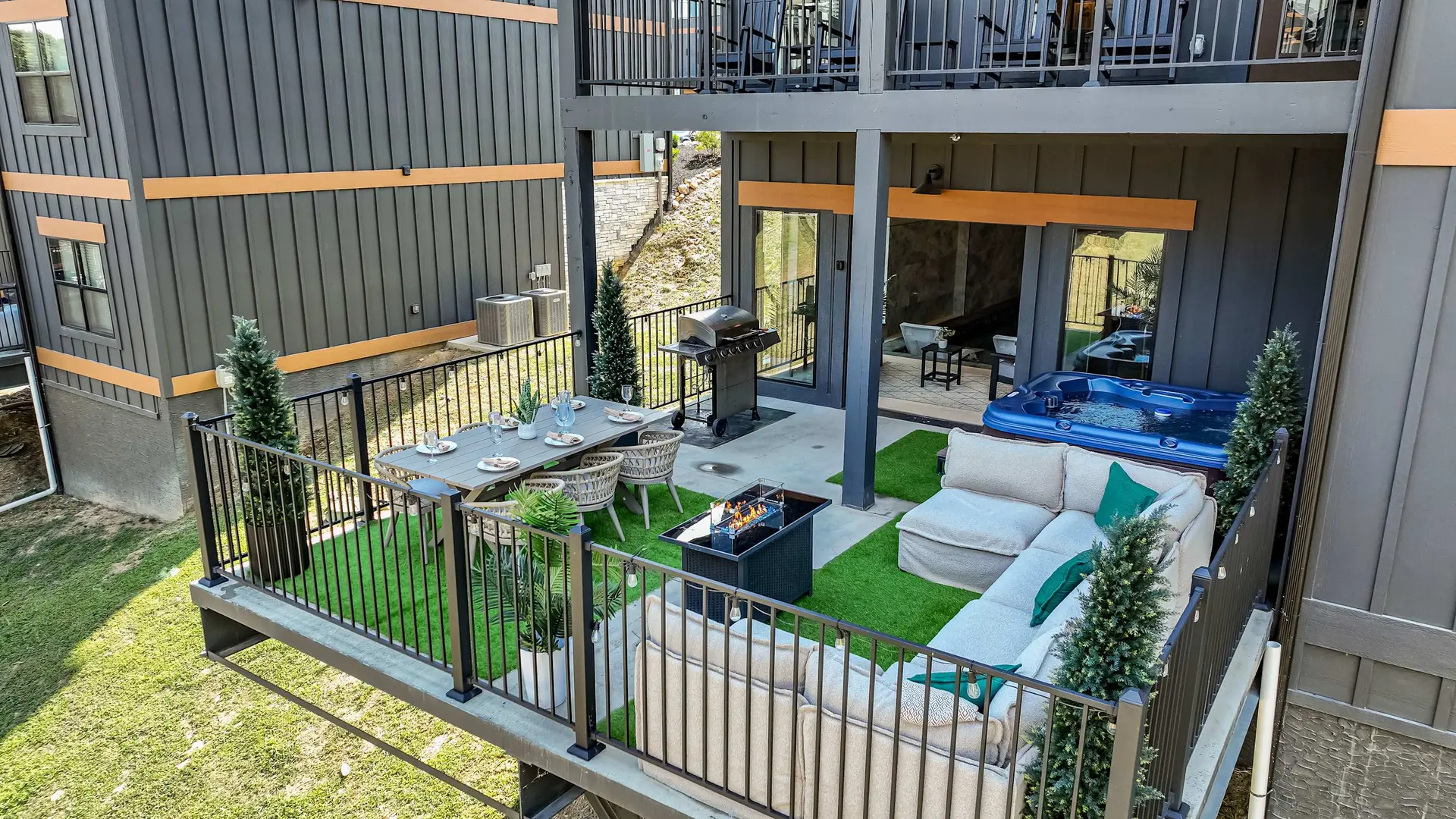 An outdoor living space with a dining table, sofa, hot tub, and grill.